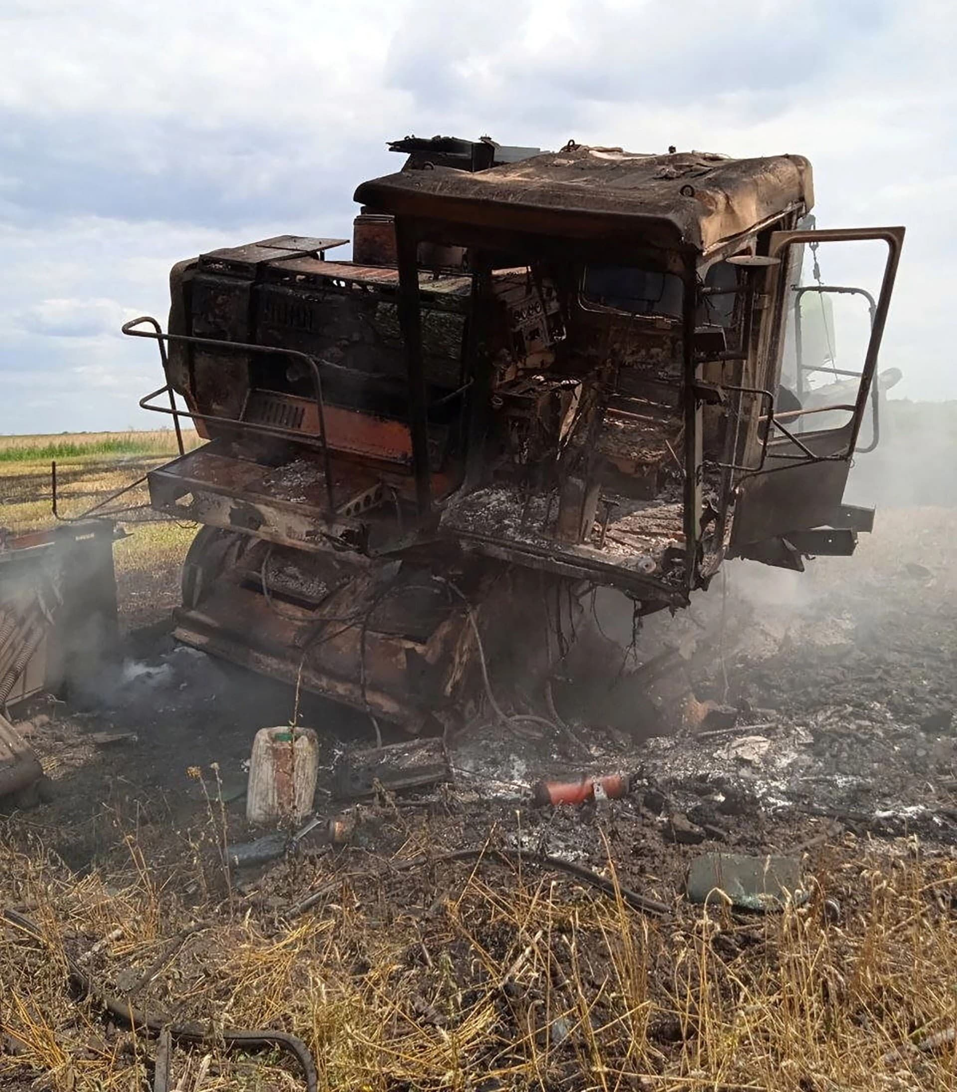 A burning harvest combine that exploded on an anti-tank mine is seen in a wheat field in Vilkhivka
