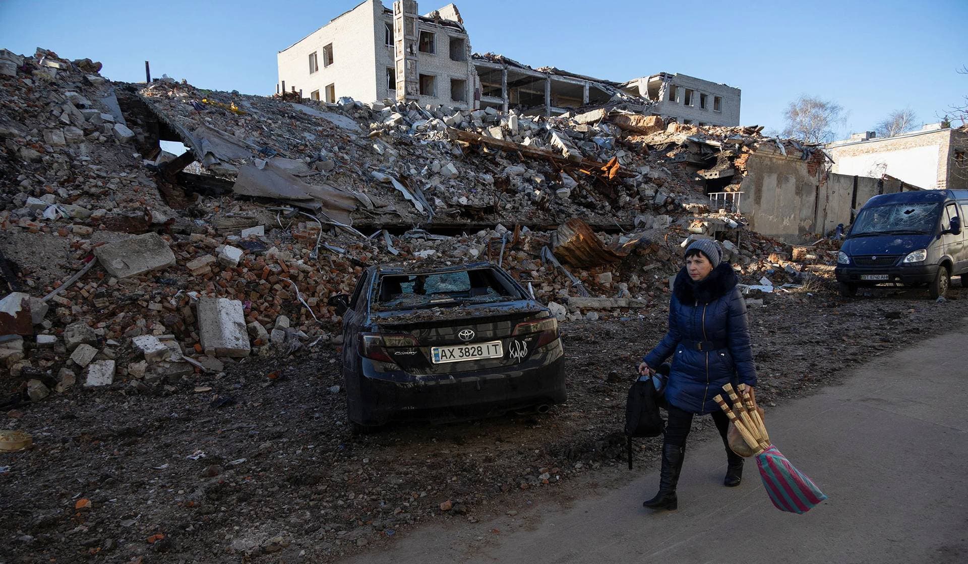 A woman walks past a building destroyed by a Russian missile strike in Kharkiv