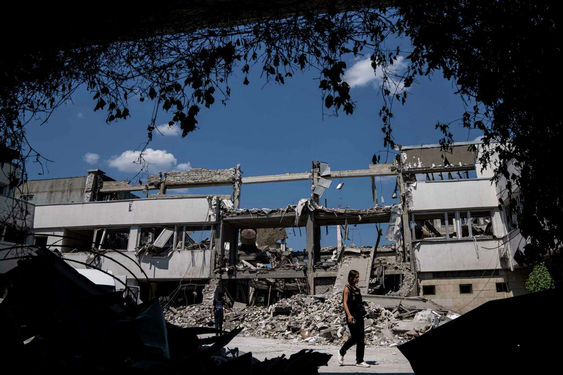 Ukrainian journalists walk in the yard of National Pedagogic university destroyed by a Russian attack in Kharkiv
