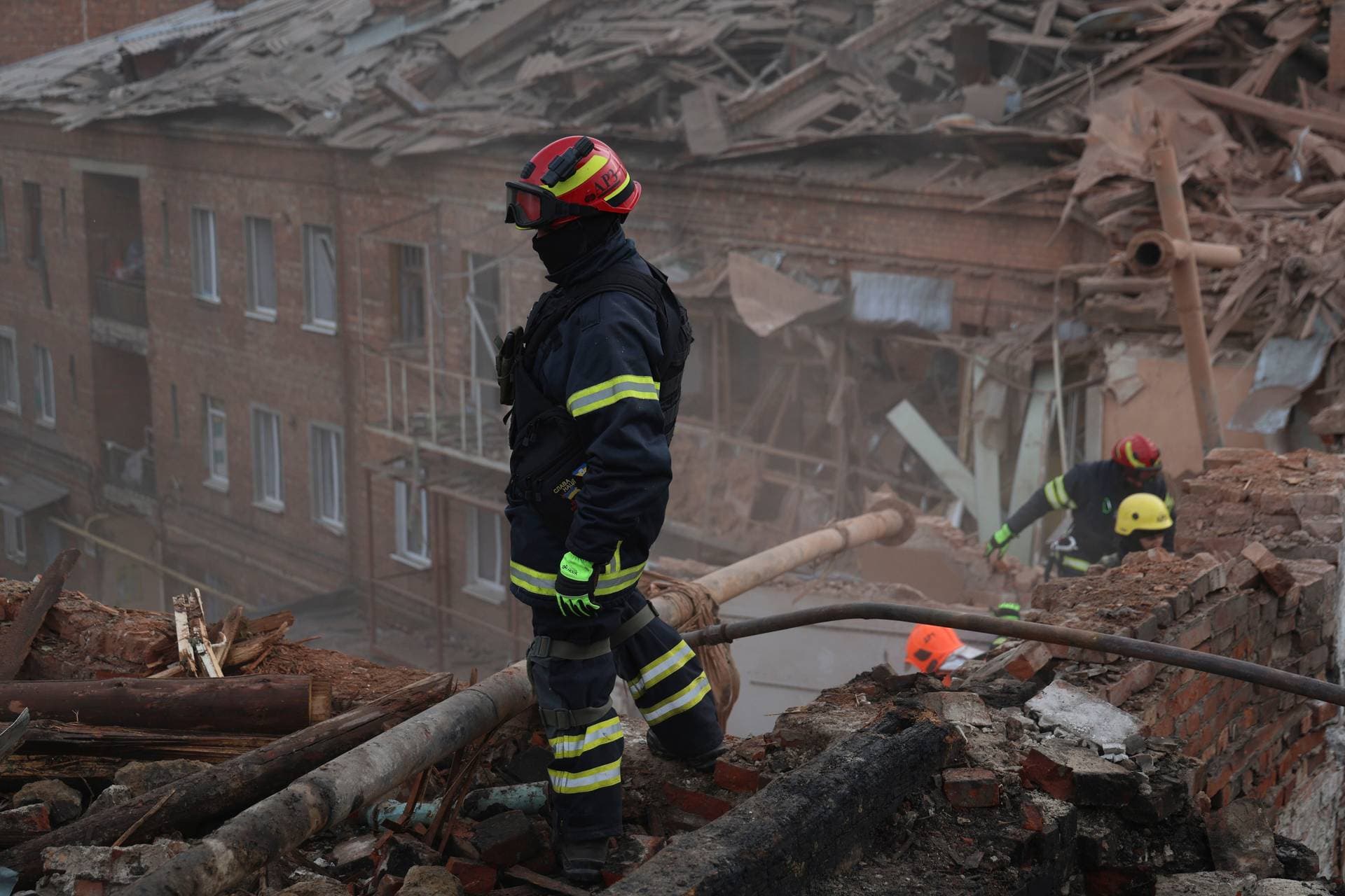 Emergency workers search for victims after a Russian air attack that damaged an apartment building in Kharkiv