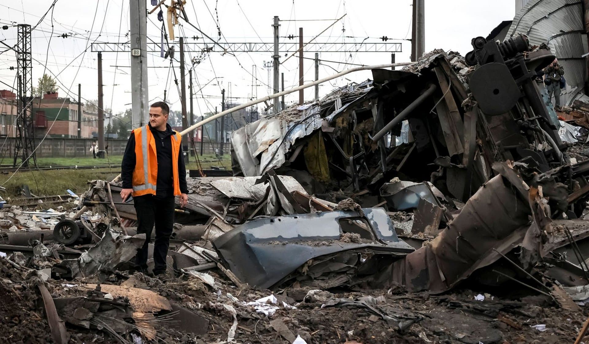 A worker stands near train cars destroyed by a Russian military strike at a freight railway station in Kharkiv