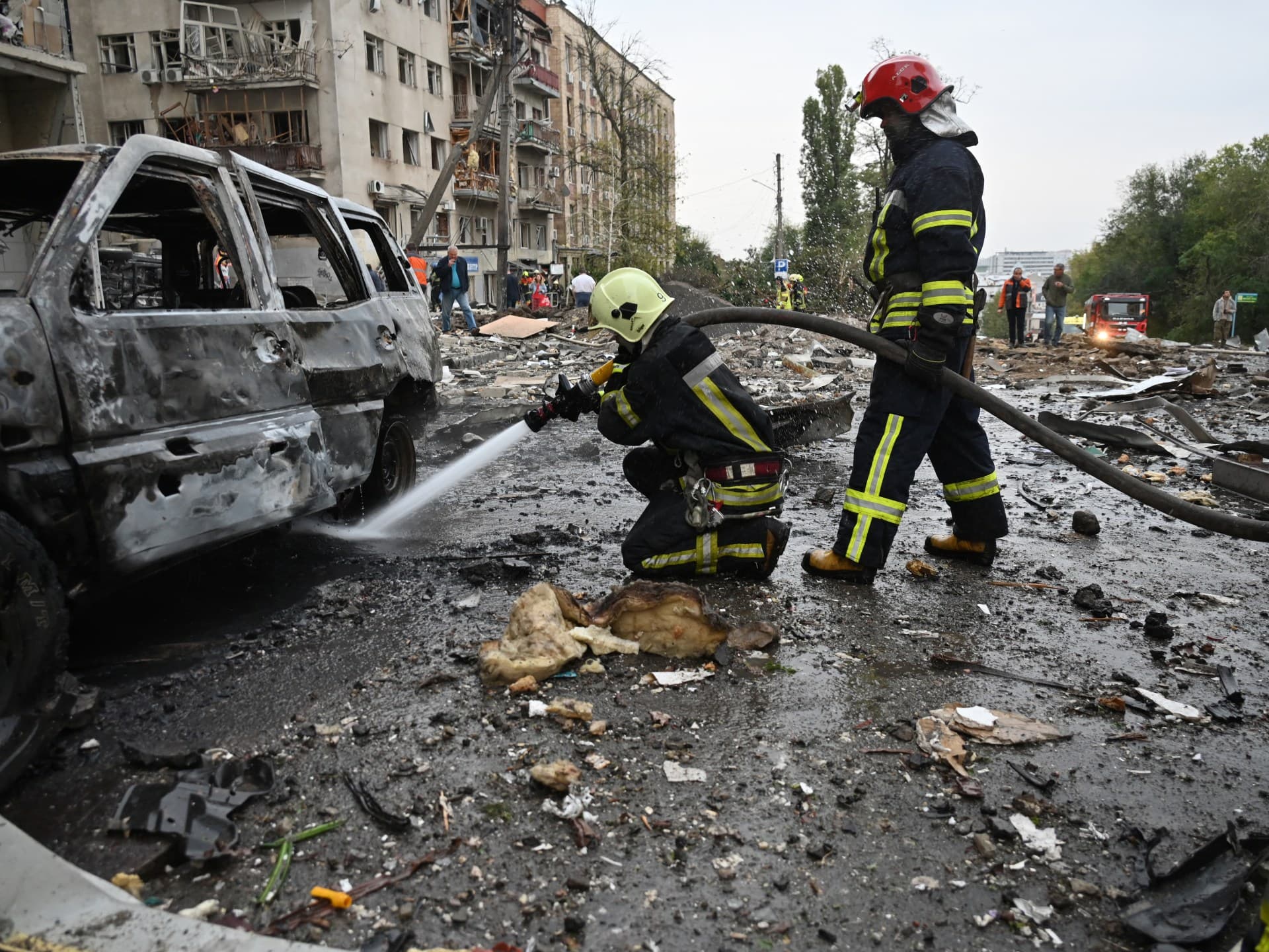 Firefighters douse a burning car after a Russian strike in Kharkiv
