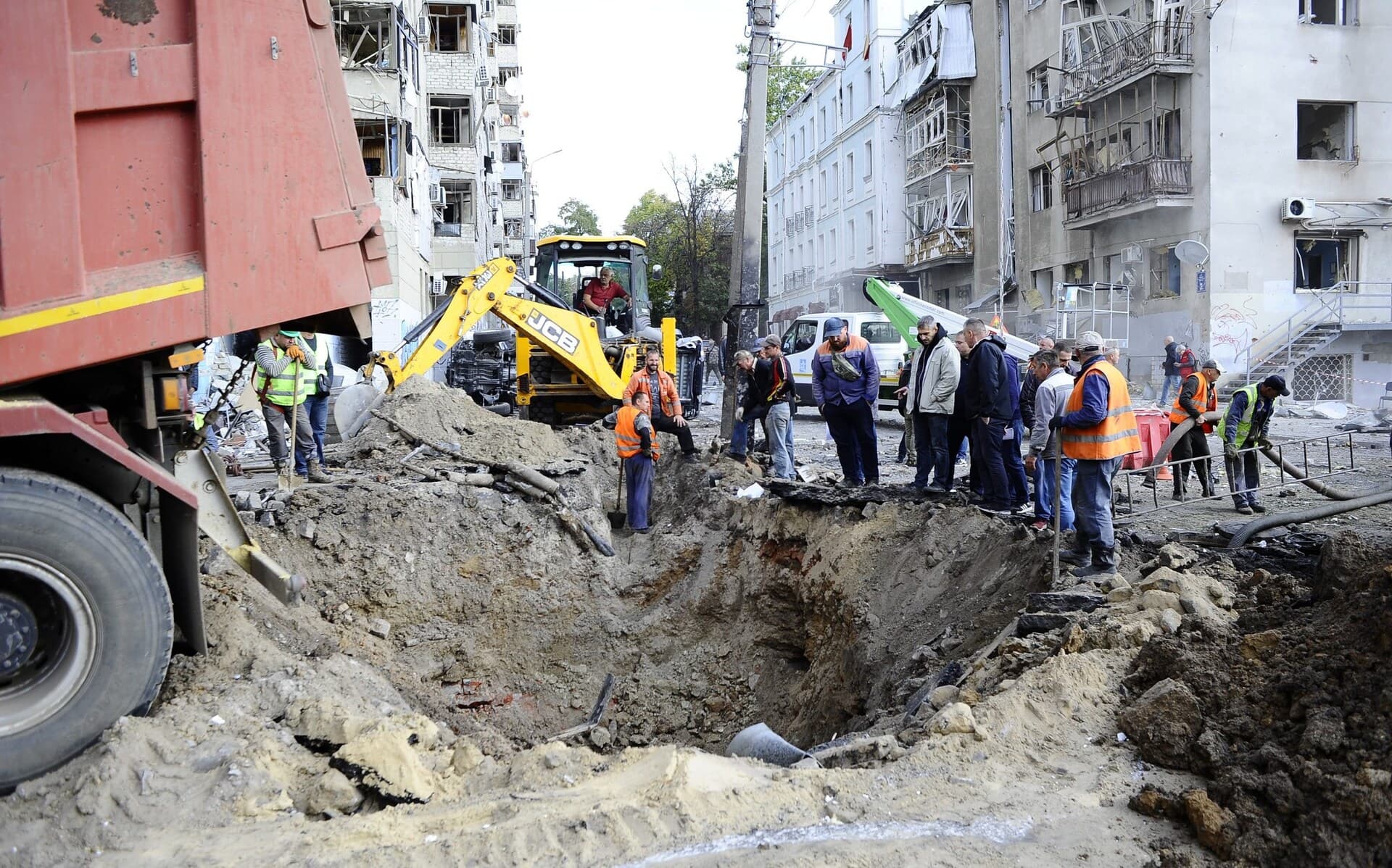 Utility workers are filling up a crater left by a missile hit on October 6, 2023 in Kharkiv