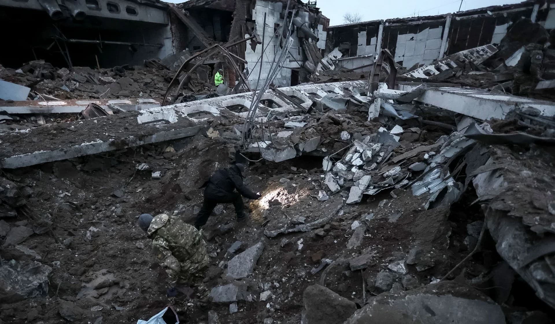 Police and investigators inspect a crater at a site of an industrial area destroyed by a Russian missile strike in Kharkiv