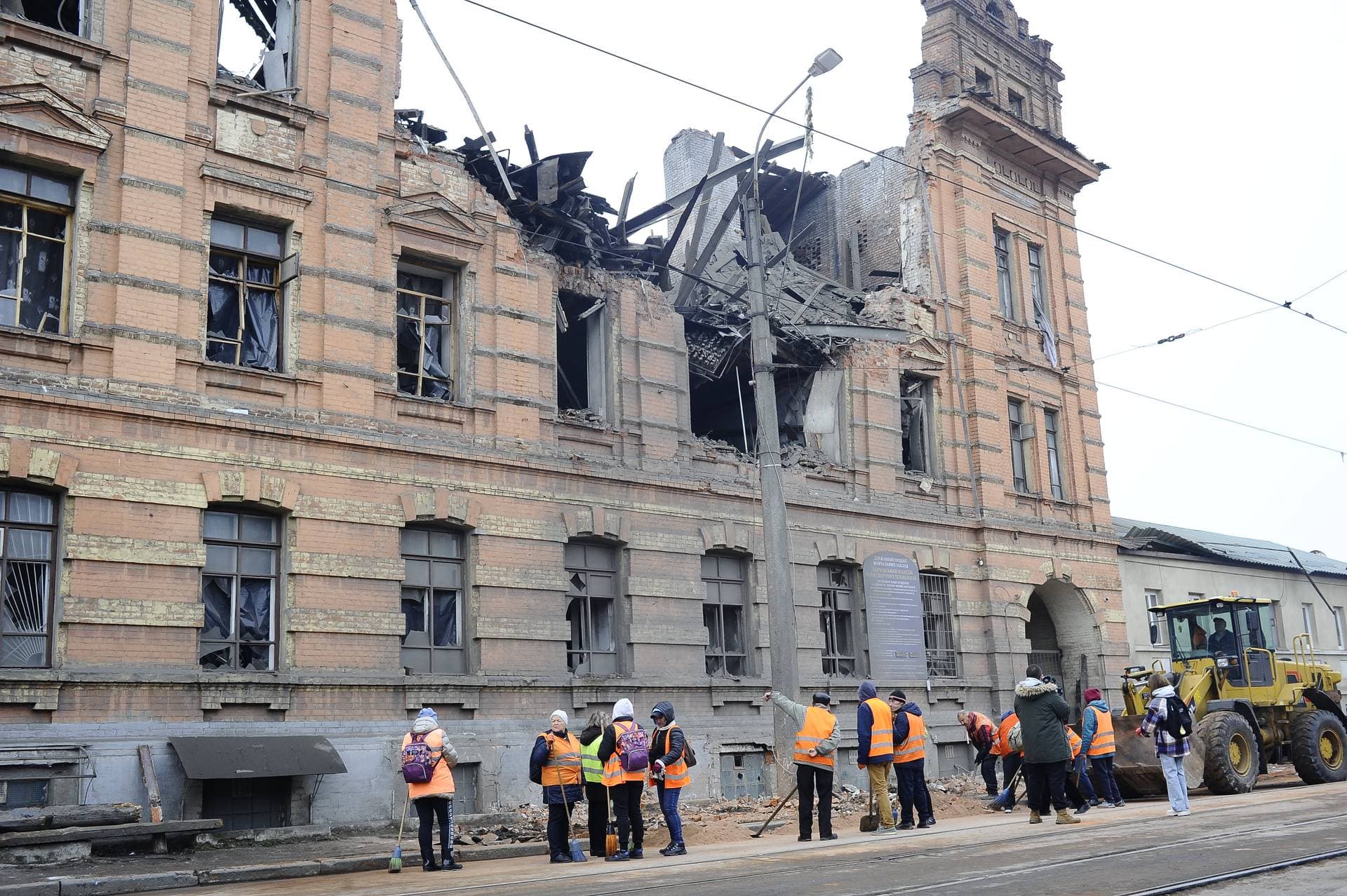 City utility workers stand outside the destroyed building of the Kharkiv College of Transport Technologies