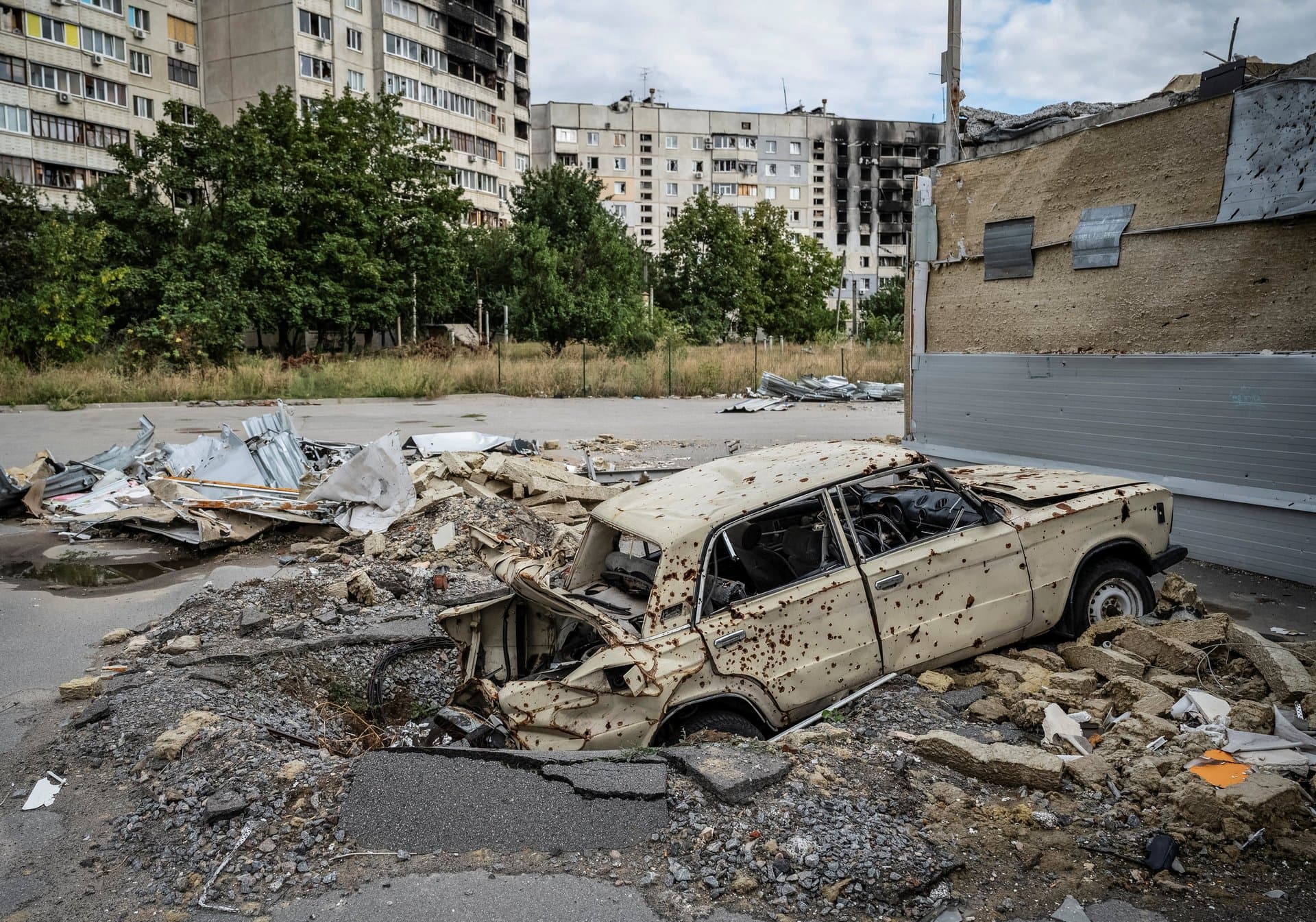 A destroyed car is pictured in front of a damaged residential building on Tuesday in Saltivka