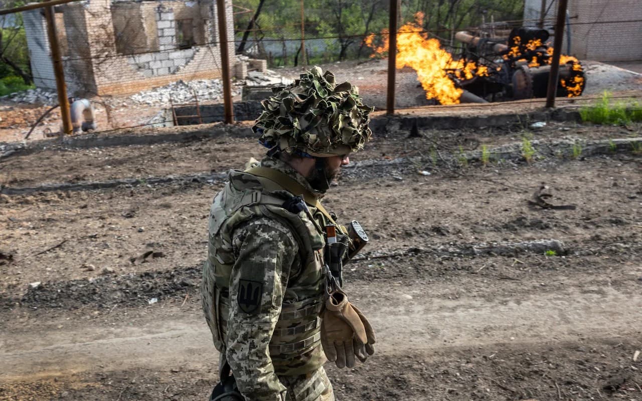 A Ukrainian soldier walks past a burning gas terminal on the northern outskirts of Kharkiv