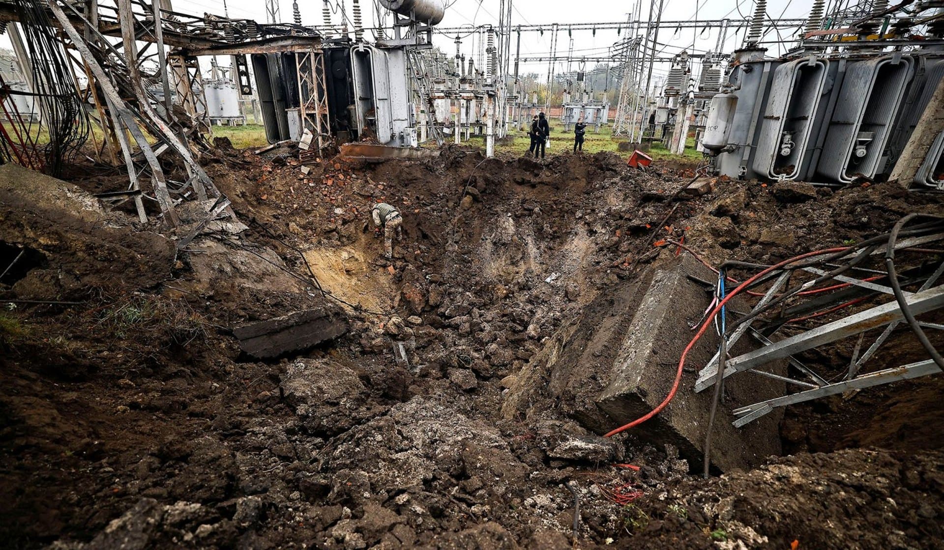 Investigators inspect a crater left by a Russian missile strike at an electrical transformer facility in Kharkiv