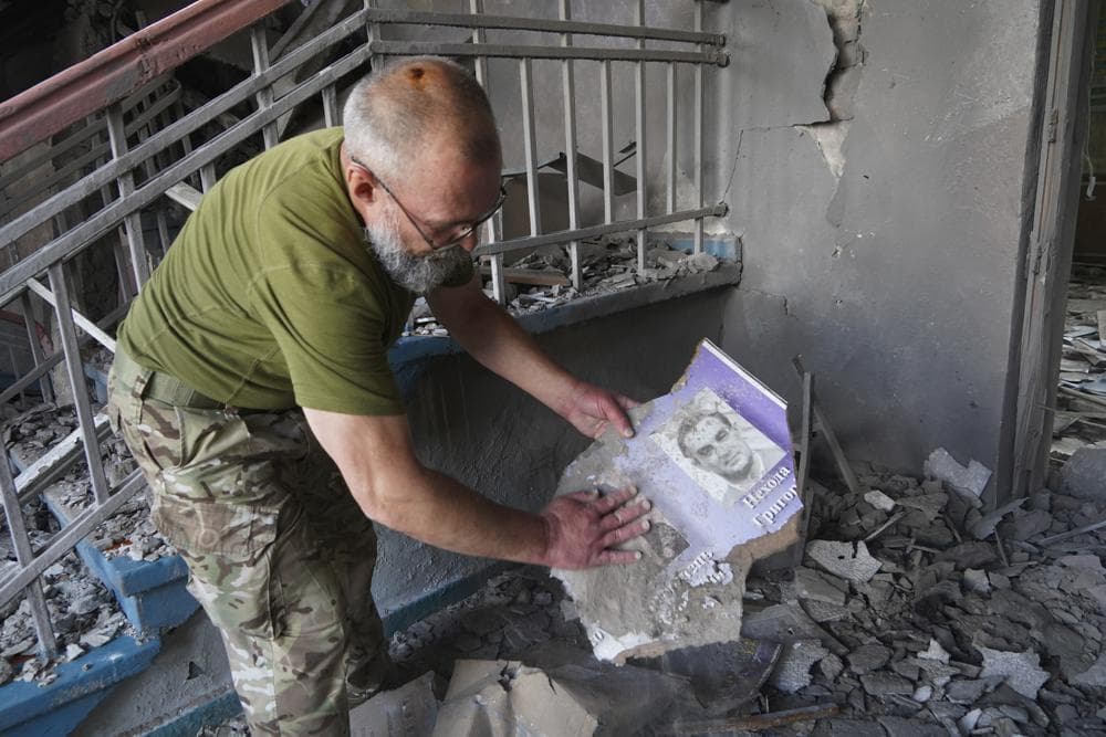 A Ukrainian serviceman searches through the rubble of a school that was destroyed some days ago during a missile strike in outskirts of Kharkiv