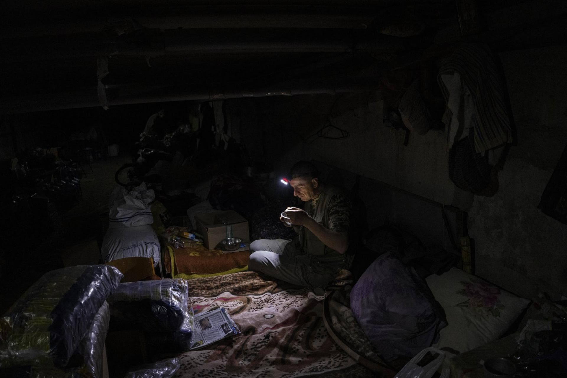 A Ukrainian man eats inside a basement used as an improvised bomb shelter in Kutuzivka