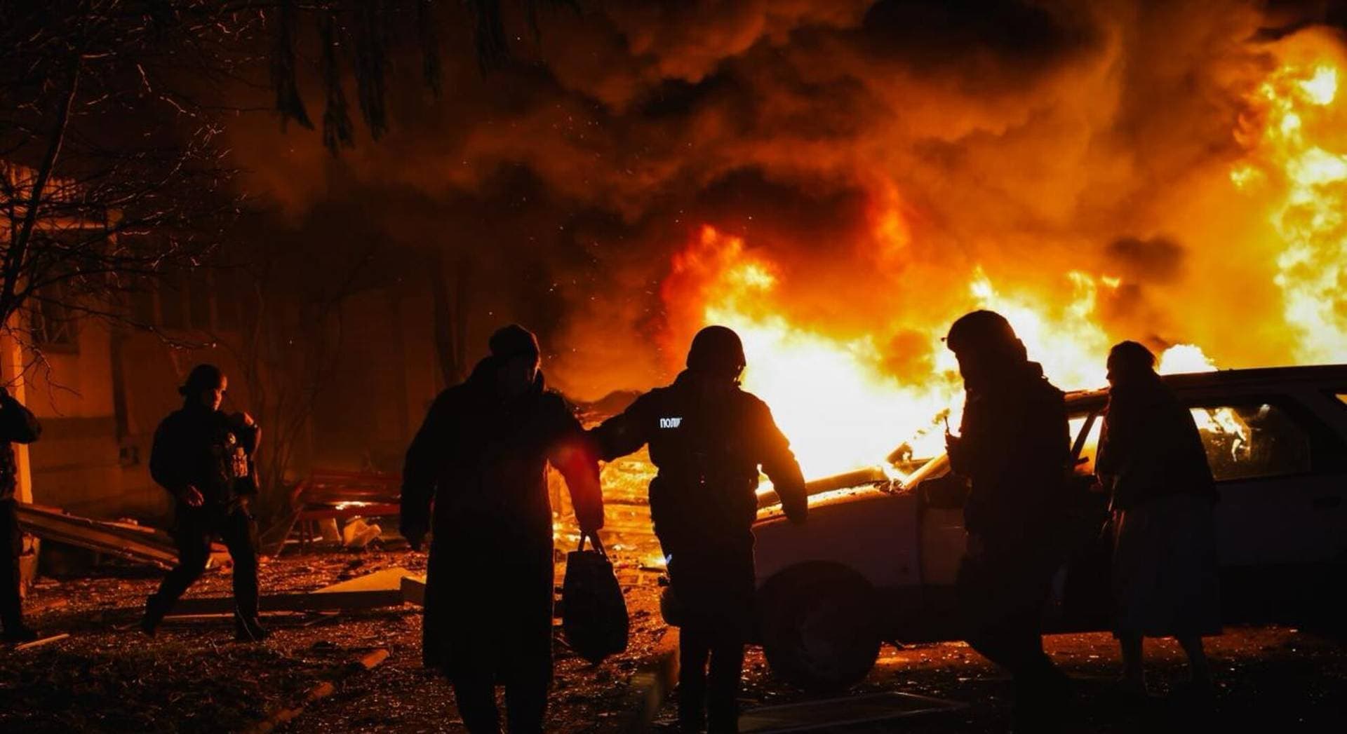 A police officer evacuates a resident from the apartment building hit by a Russian drone strike in Kharkiv