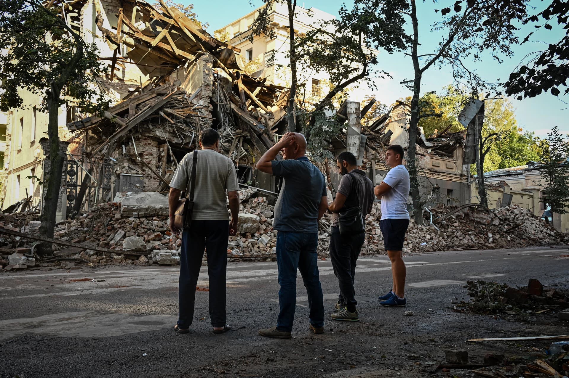 Passersby stand near a destroyed building following an overnight missile strike in Kharkiv