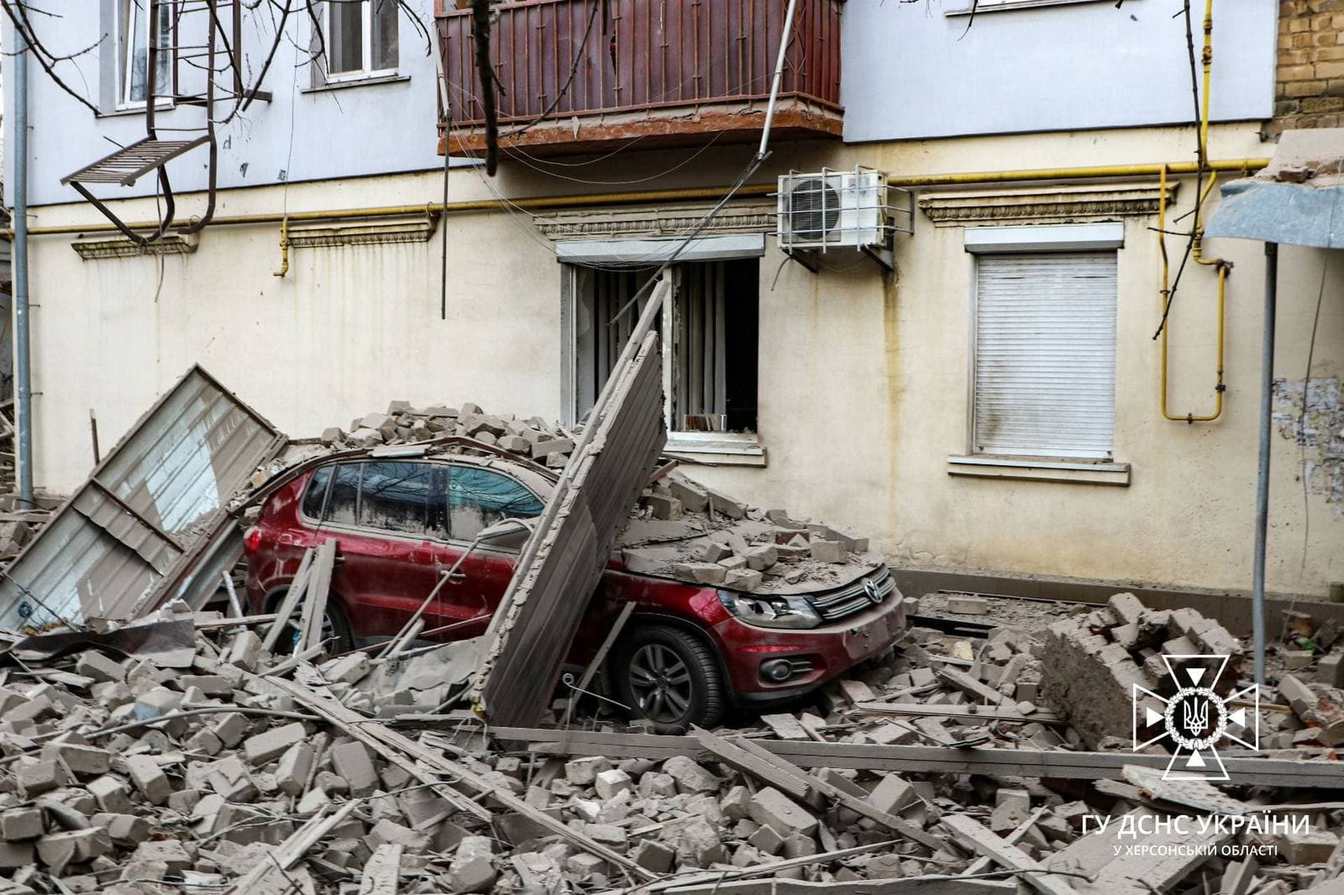 A car lies under debris outside a building damaged as a result of a Russian air strike on Kherson