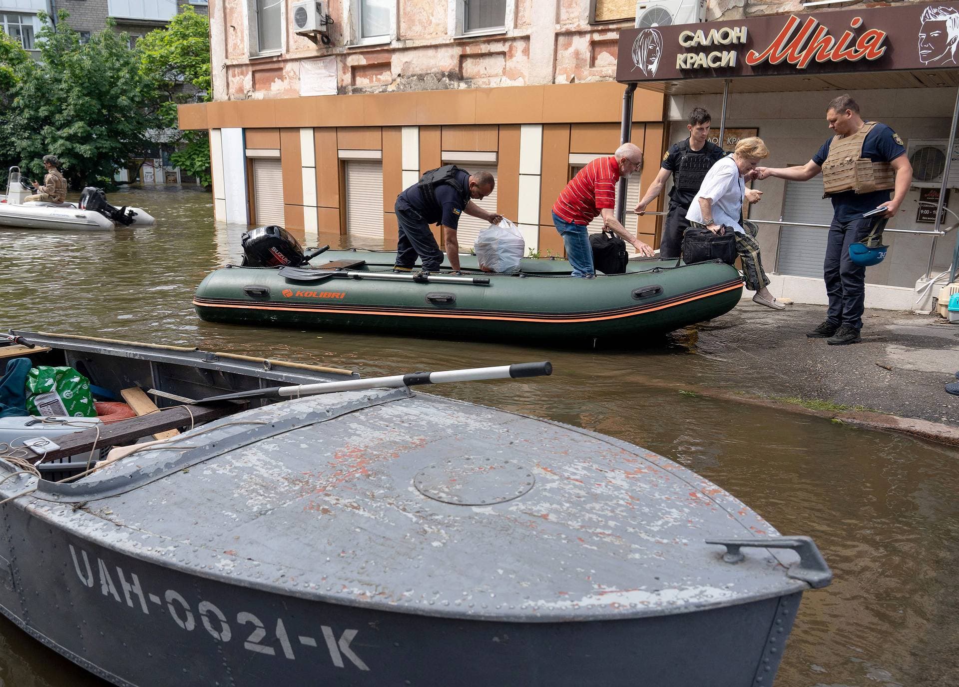 Ukrainian security forces help to unload local residents from a boat during an evacuation from a flooded area in Kherson