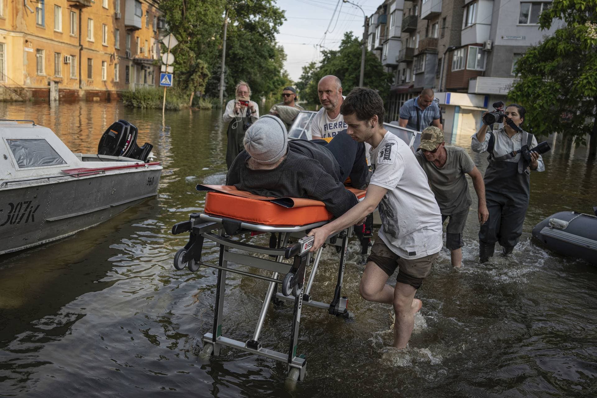 Volunteers haul a woman on a stretcher as she been evacuated from a flooded neighborhood of the left bank Dnipro river in Kherson