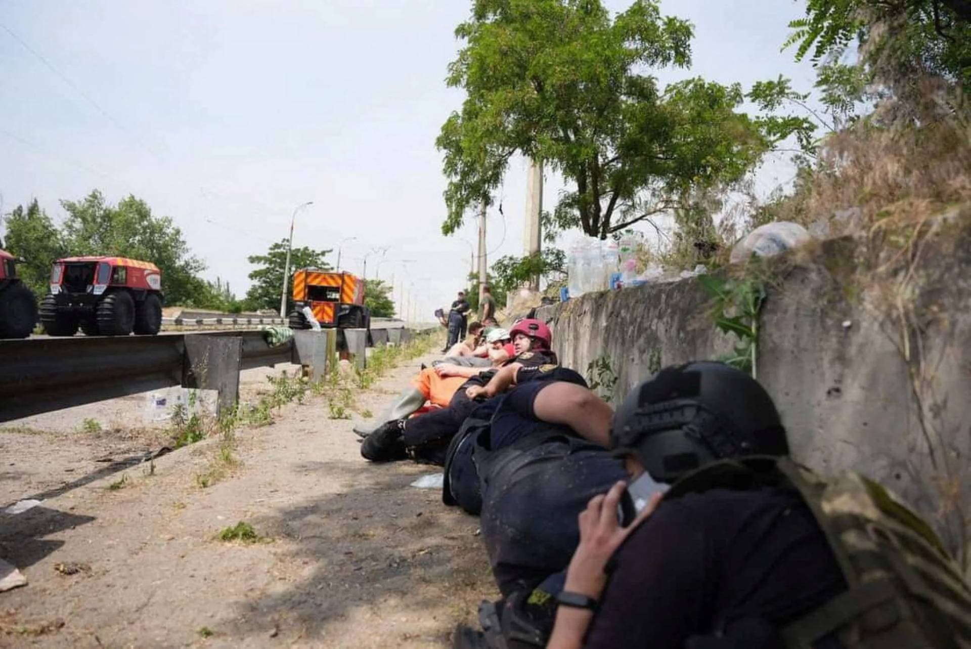 Emergency workers take cover during a Russian military strike while they evacuate people from a flooded area in Kherson