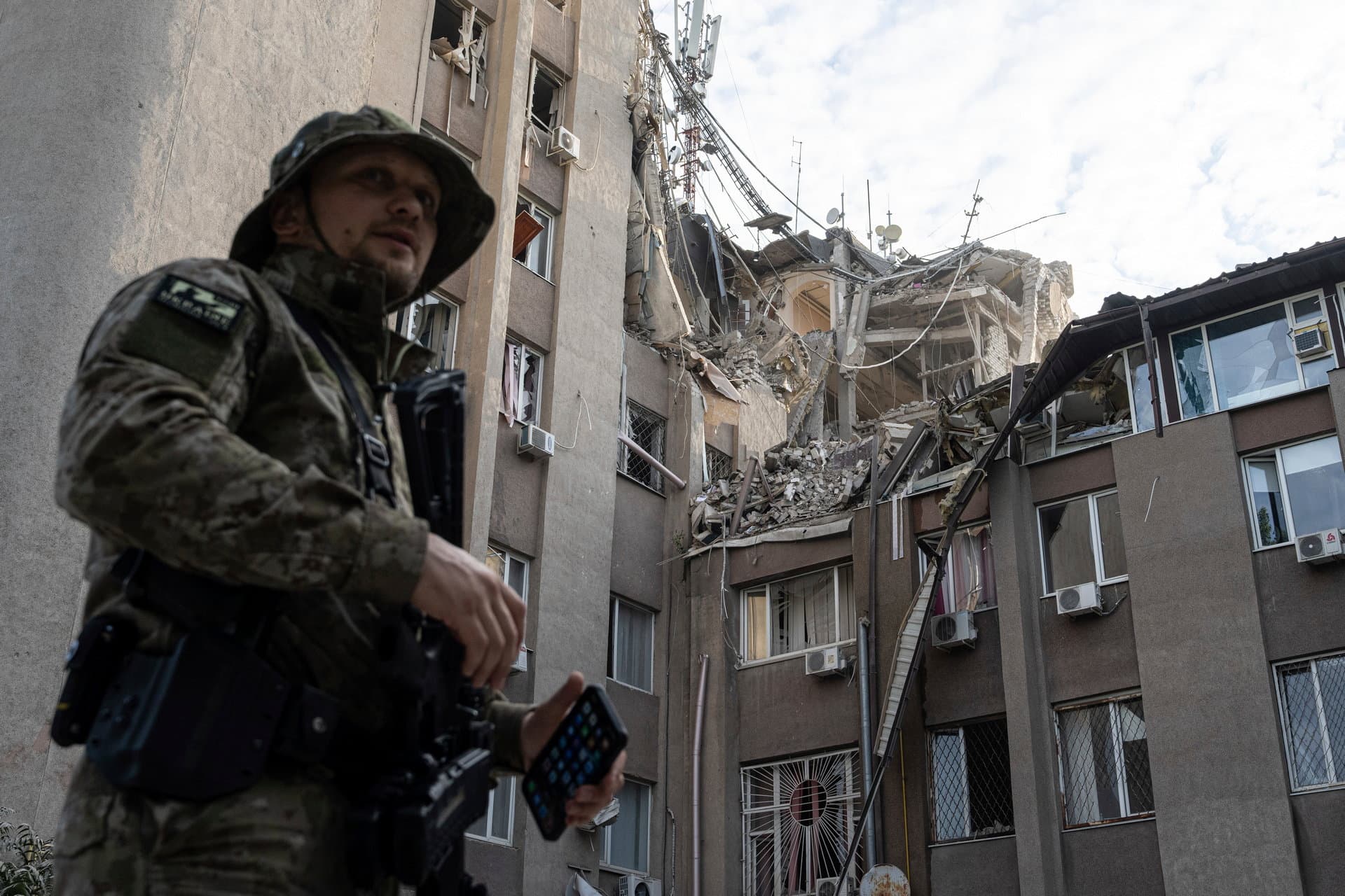 A Ukrainian serviceman stands in front of a building which was heavily damaged by a Russian airstrike in Kherson