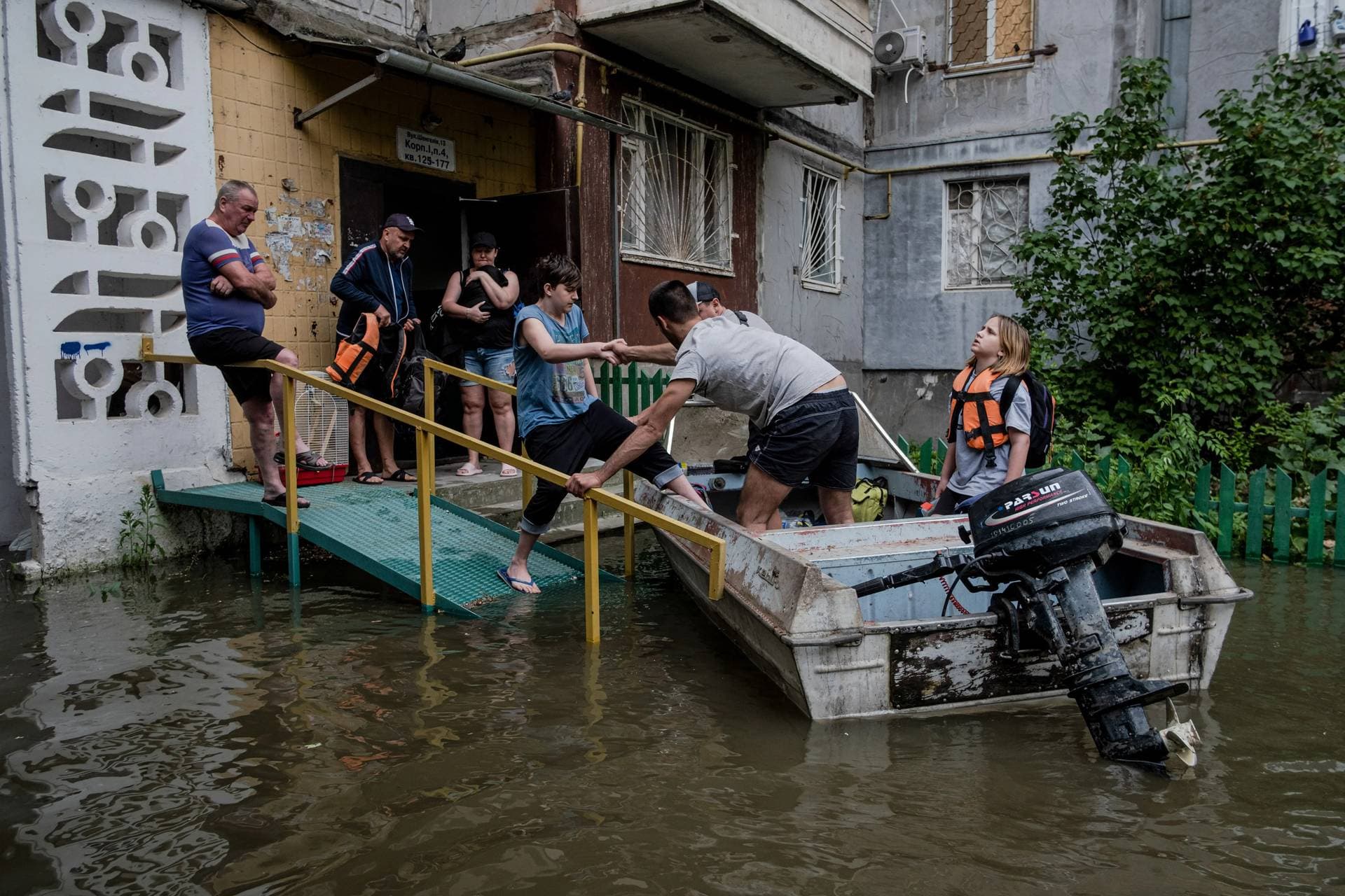 Residents evacuate from their building in a flooded area of Kherson