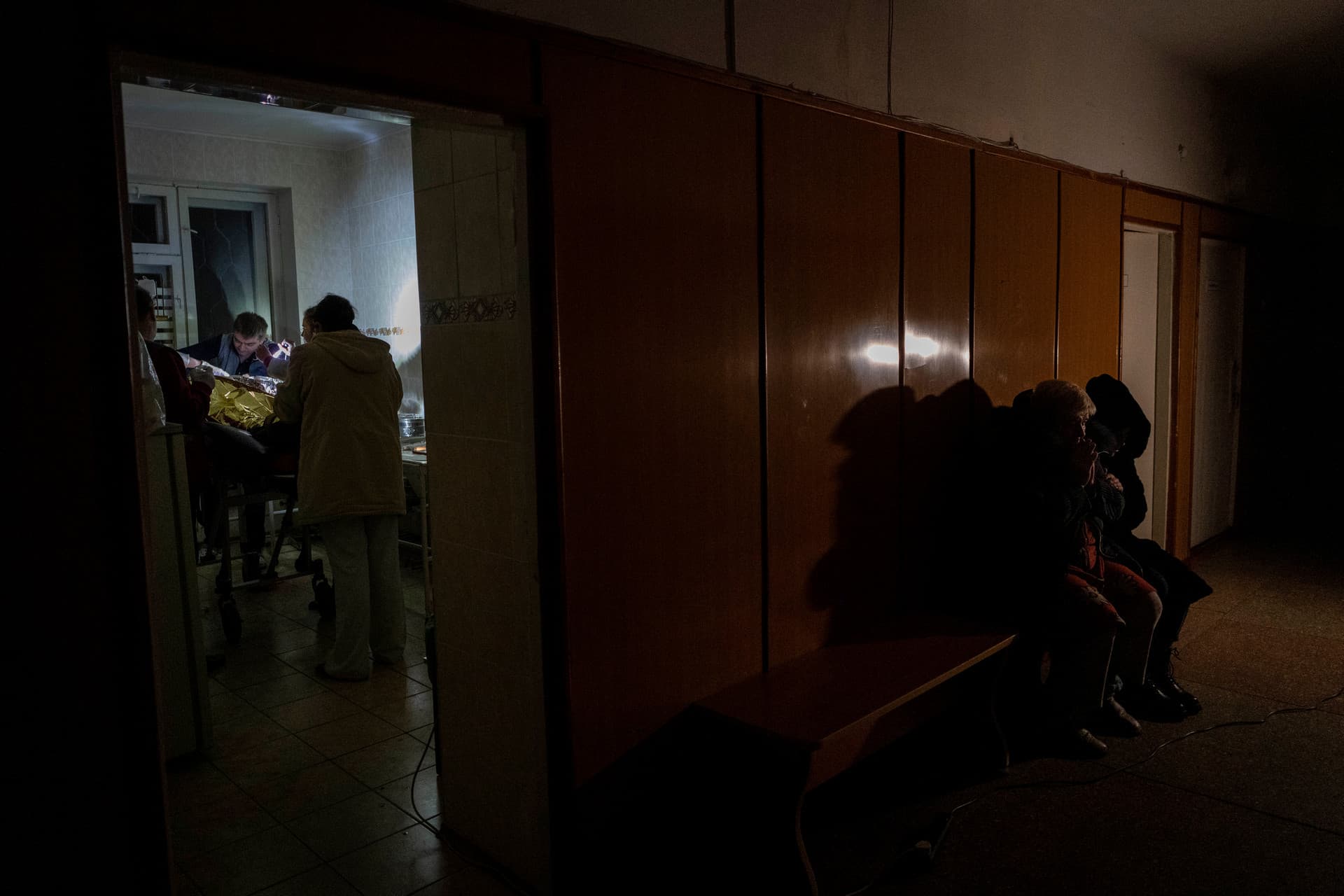 Natalia Voblikova and her daughter wait in a hospital corridor, right, as doctors stabilize Natalia's son in Kherson