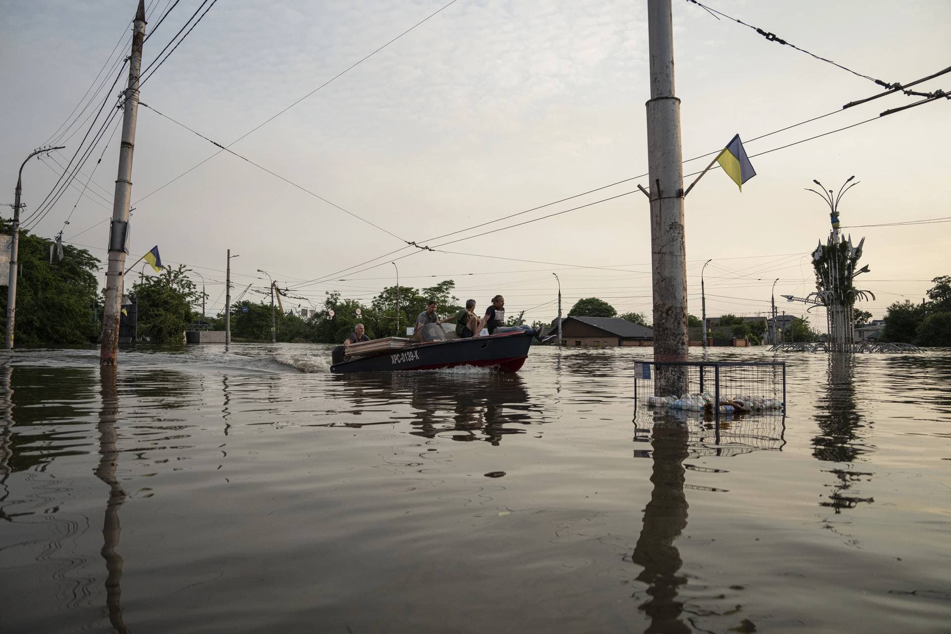 People ride by a boat through a flooded neighborhood in Kherson