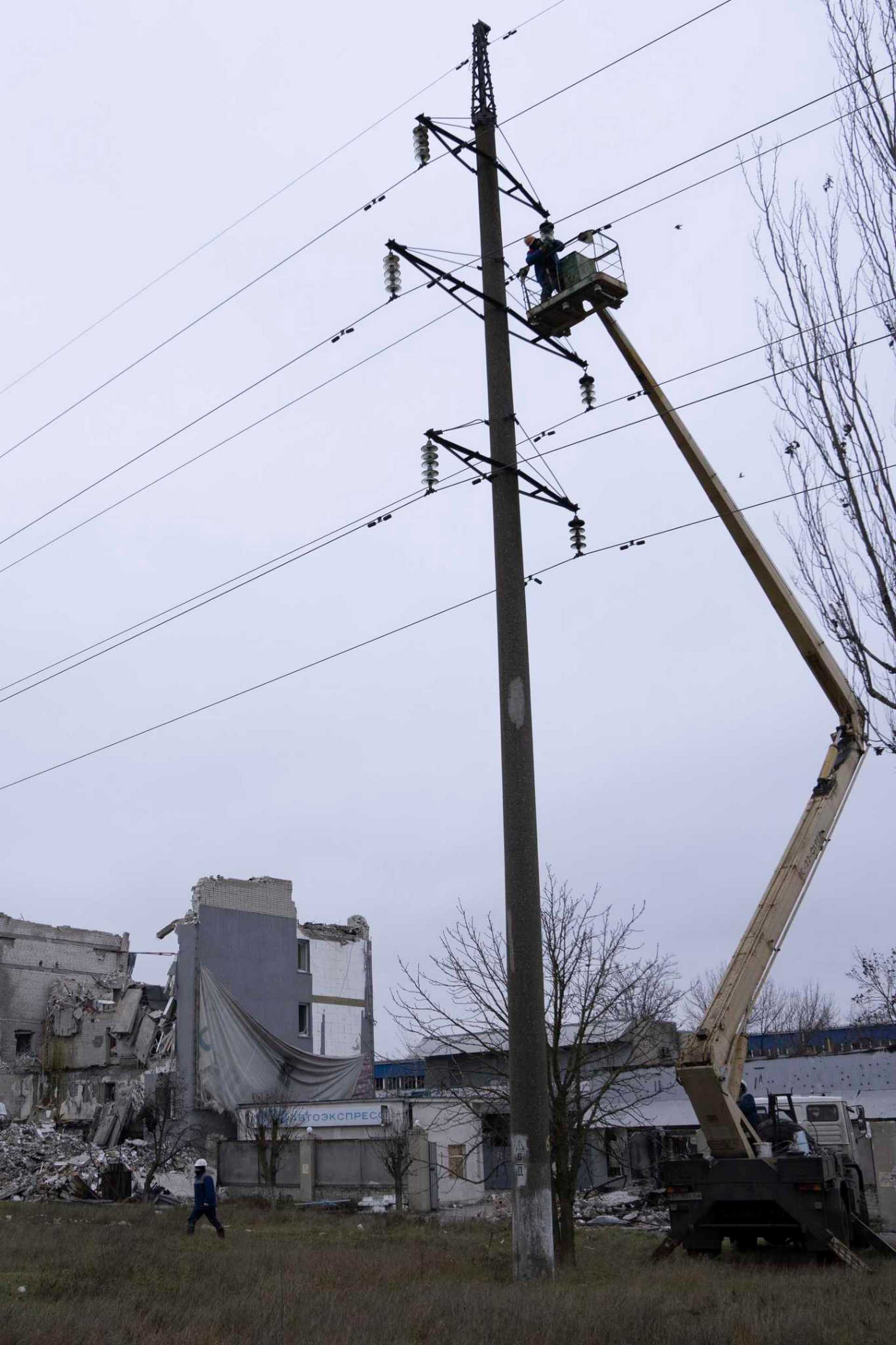 Workers repair electricity cables damaged during shelling by Russian forces in Kherson