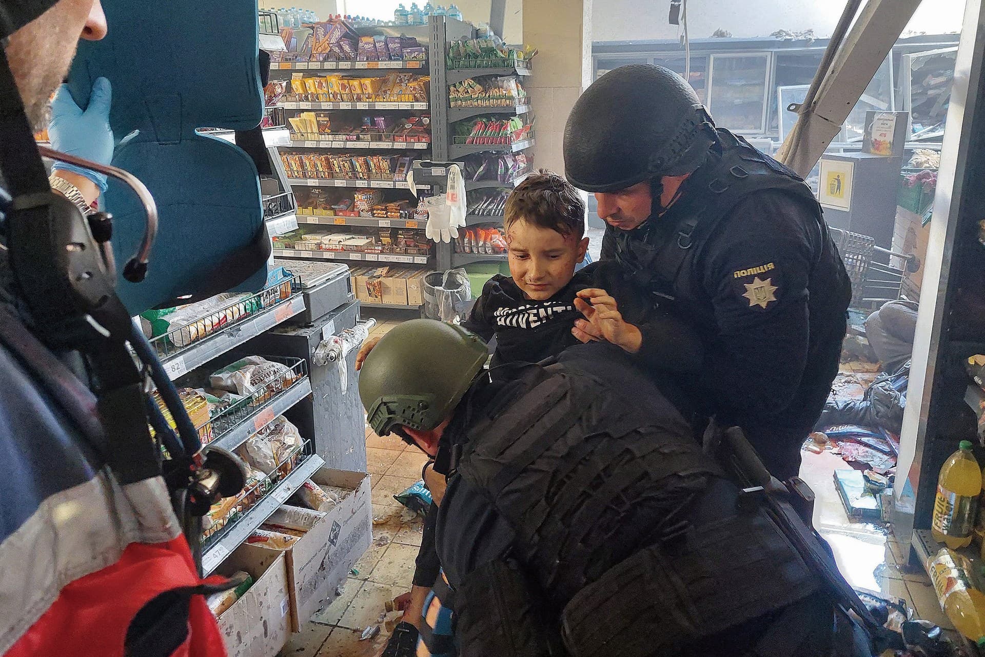 A wounded child is helped by police officers at a local supermarket following a Russian strike in Kherson