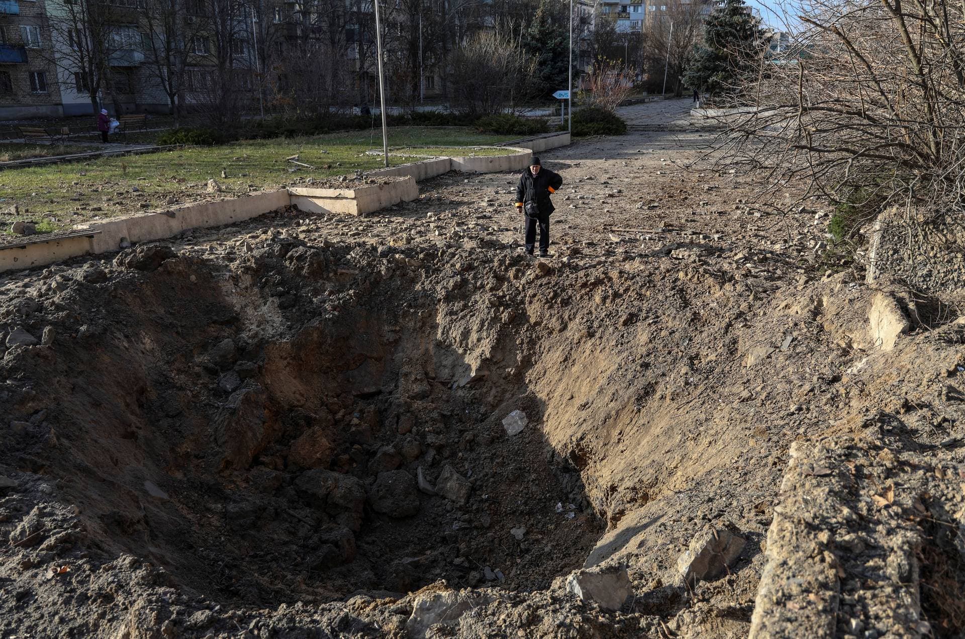 A local resident looks at a crater at the site of a Russian missile strike in Kherson