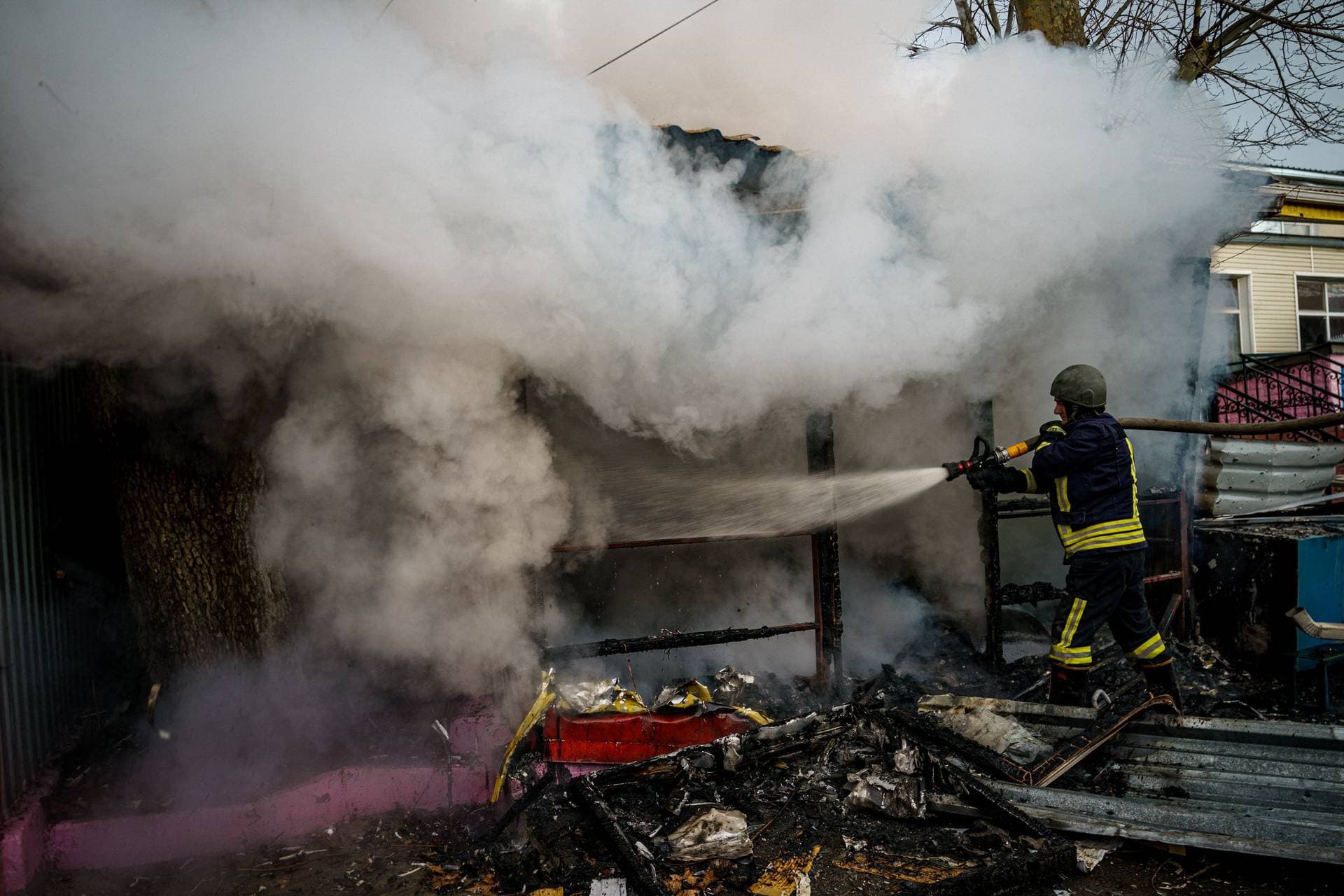 A rescuer extinguishes a fire in a burning shop in Kherson