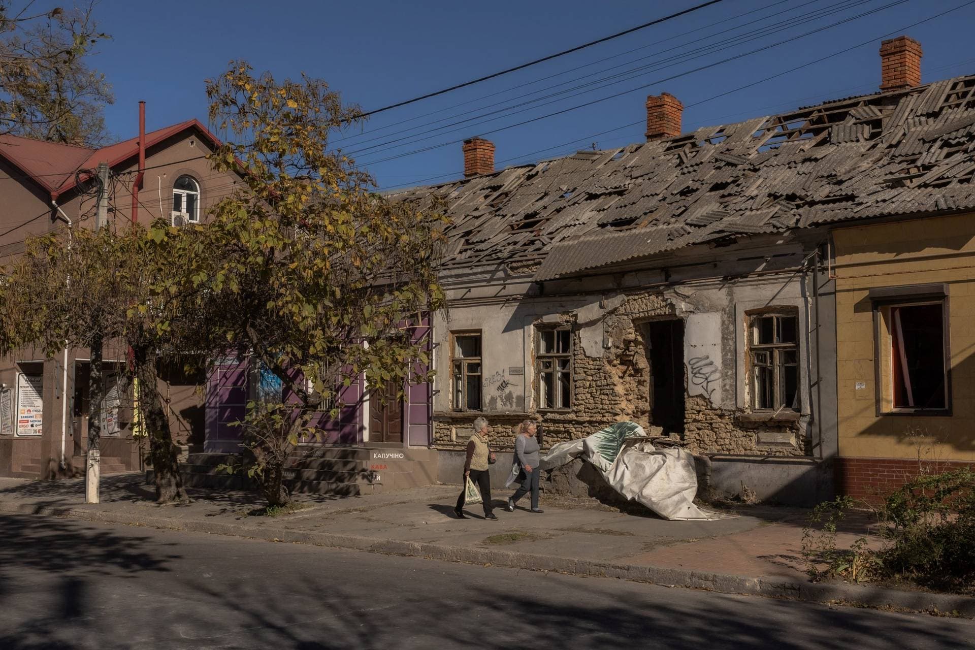 People walk past a building damaged in a recent Russian attack in Kherson