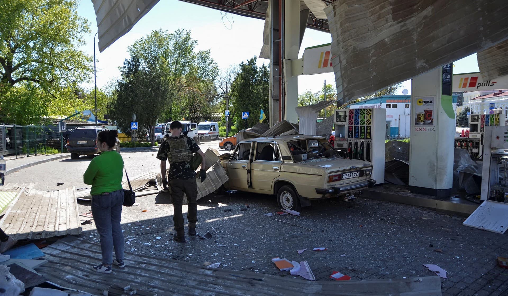 People at a gas station damaged by a Russian military strike in Kherson