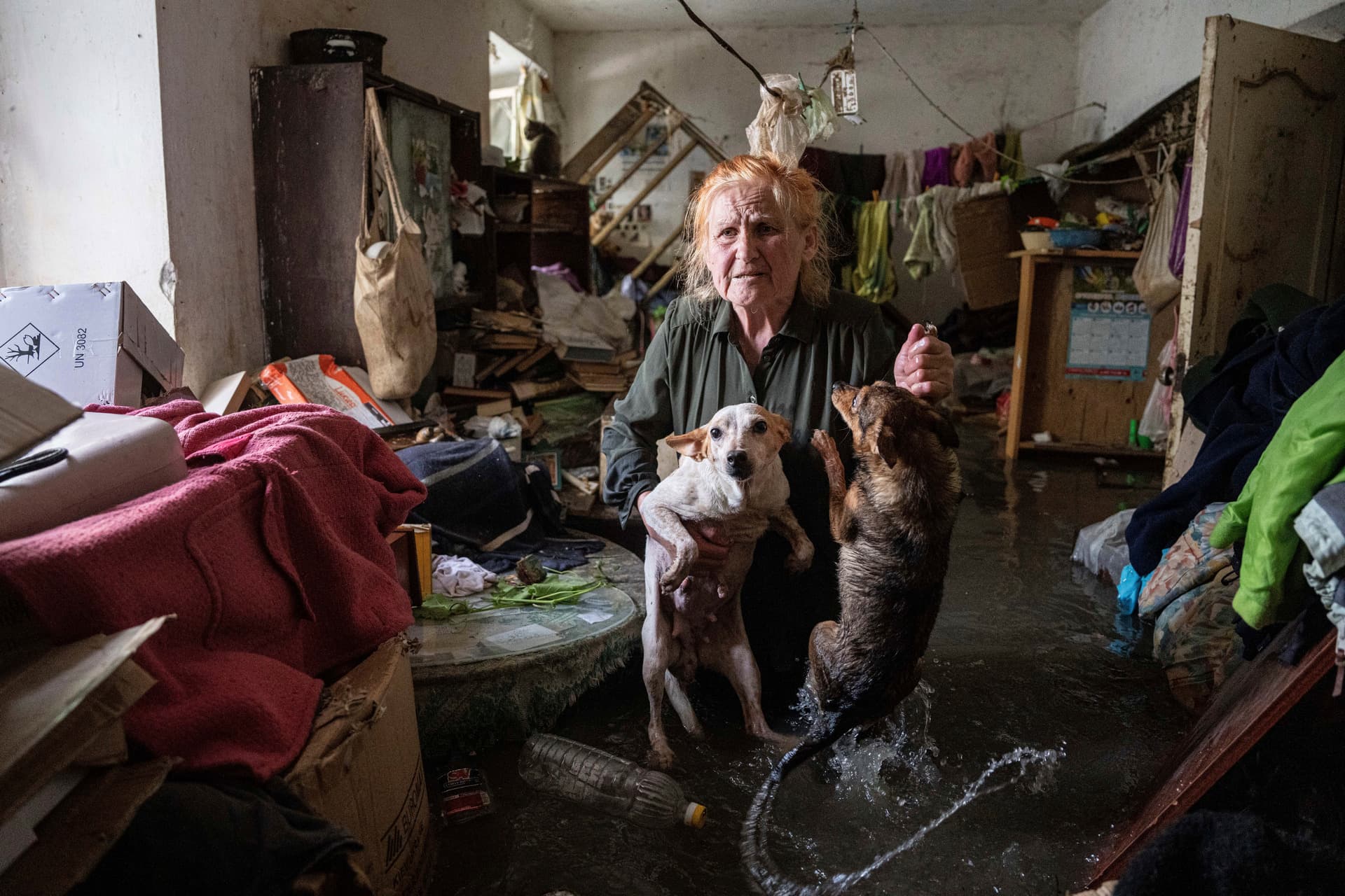 Local resident holds her pets as she stands inside her house that was flooded after the Kakhovka dam blew up overnight in Kherson