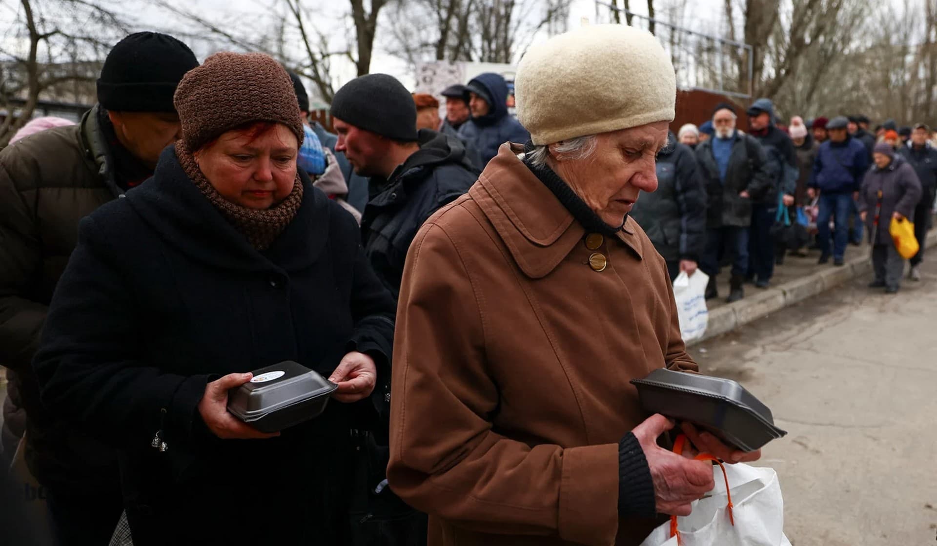 People receive meals from World Central Kitchen food truck on a street in Kherson