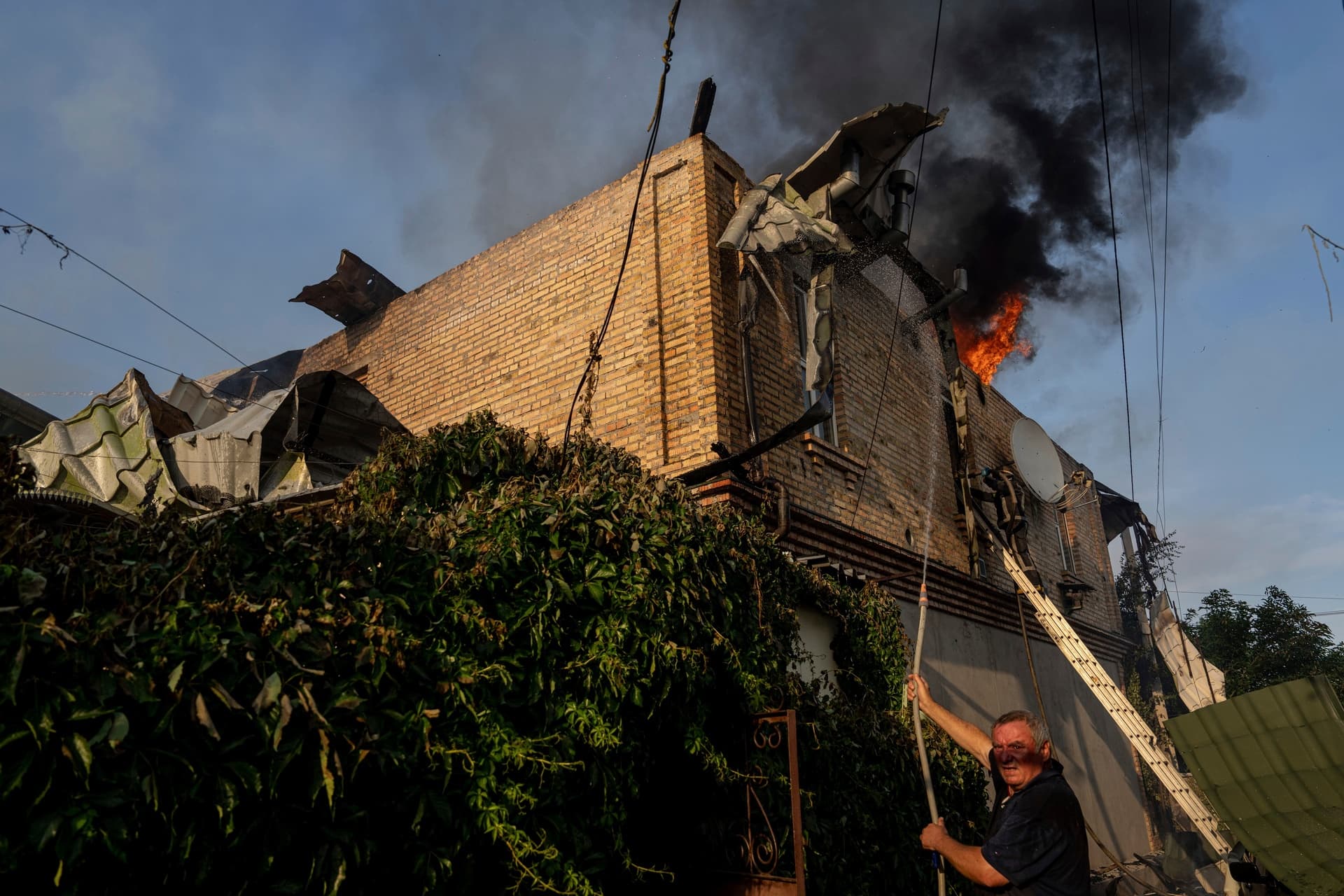 A local man extinguishing a fire of house damaged after Russian shelling in Kherson