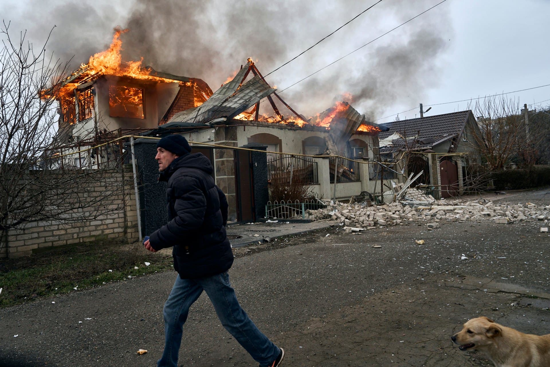 A local resident runs past a burning house hit by the Russian shelling in Kherson