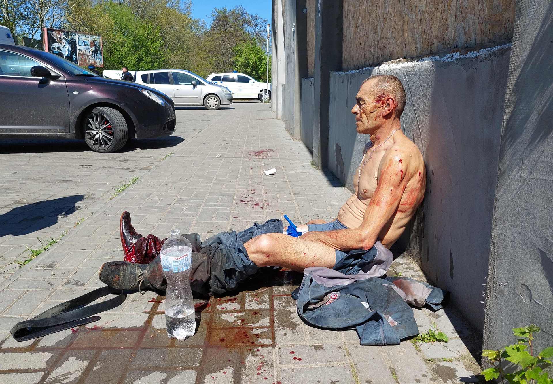 A wounded man sits outside of a local shopping center following a Russian military strike