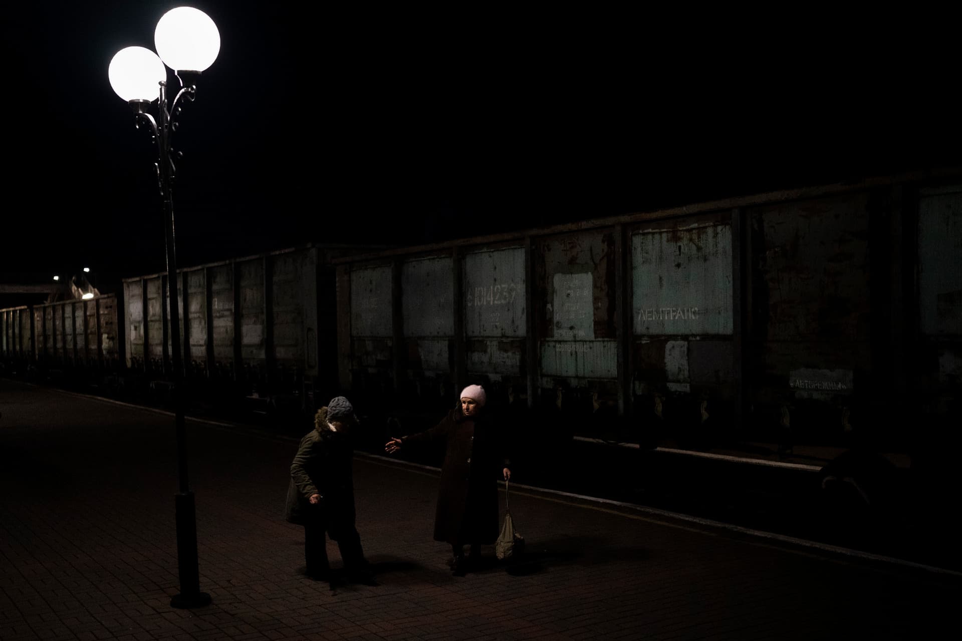 Two elderly Ukrainian women walk towards the Kherson-Kyiv train at the Kherson railway station