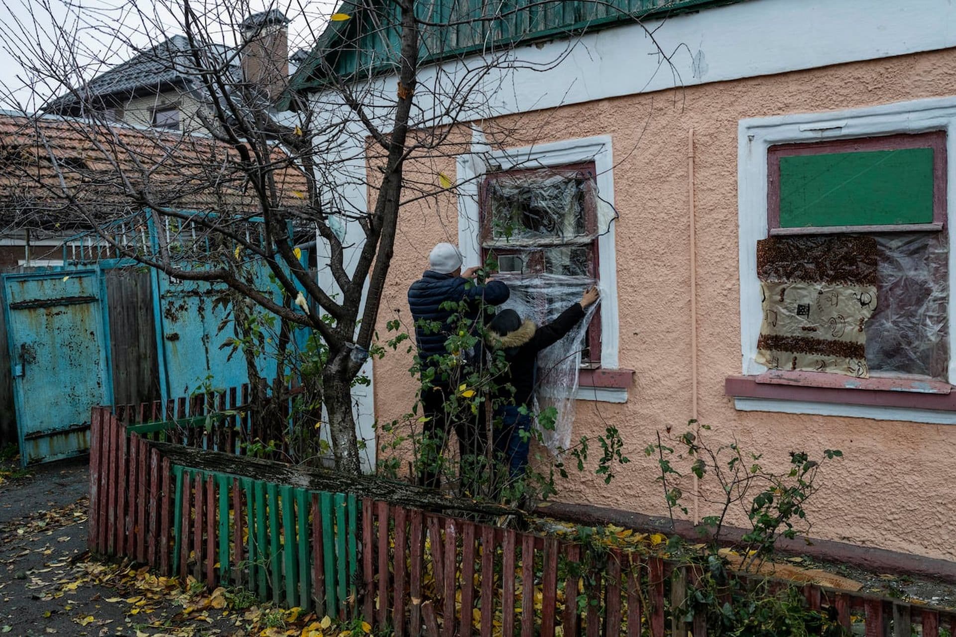 Residents cover their windows with plastic sheets the day after the house was damaged during a Russian attack in Kherson