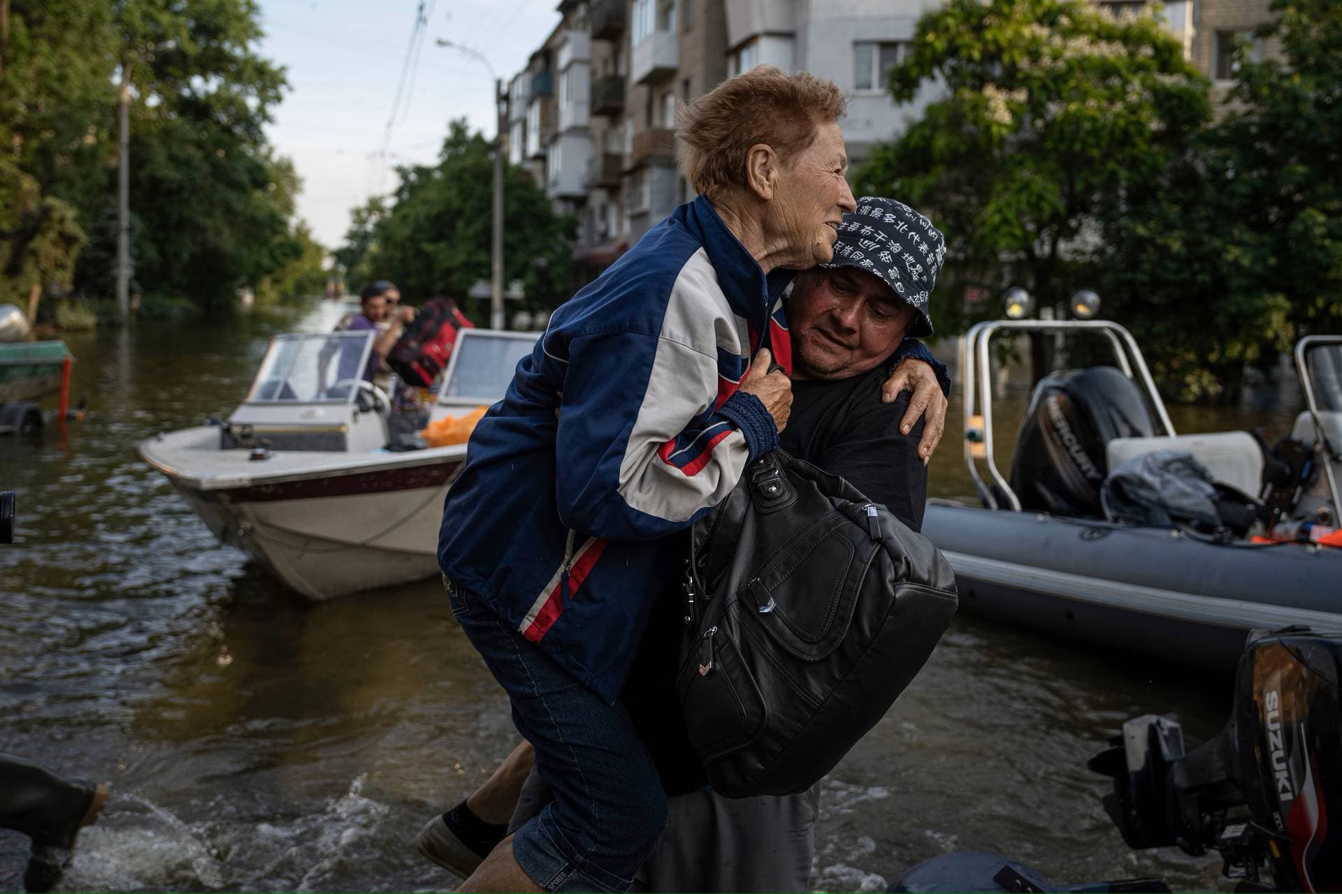 A volunteer carries a woman as she been evacuated from a flooded neighborhood of the left bank Dnipro river, in Kherson