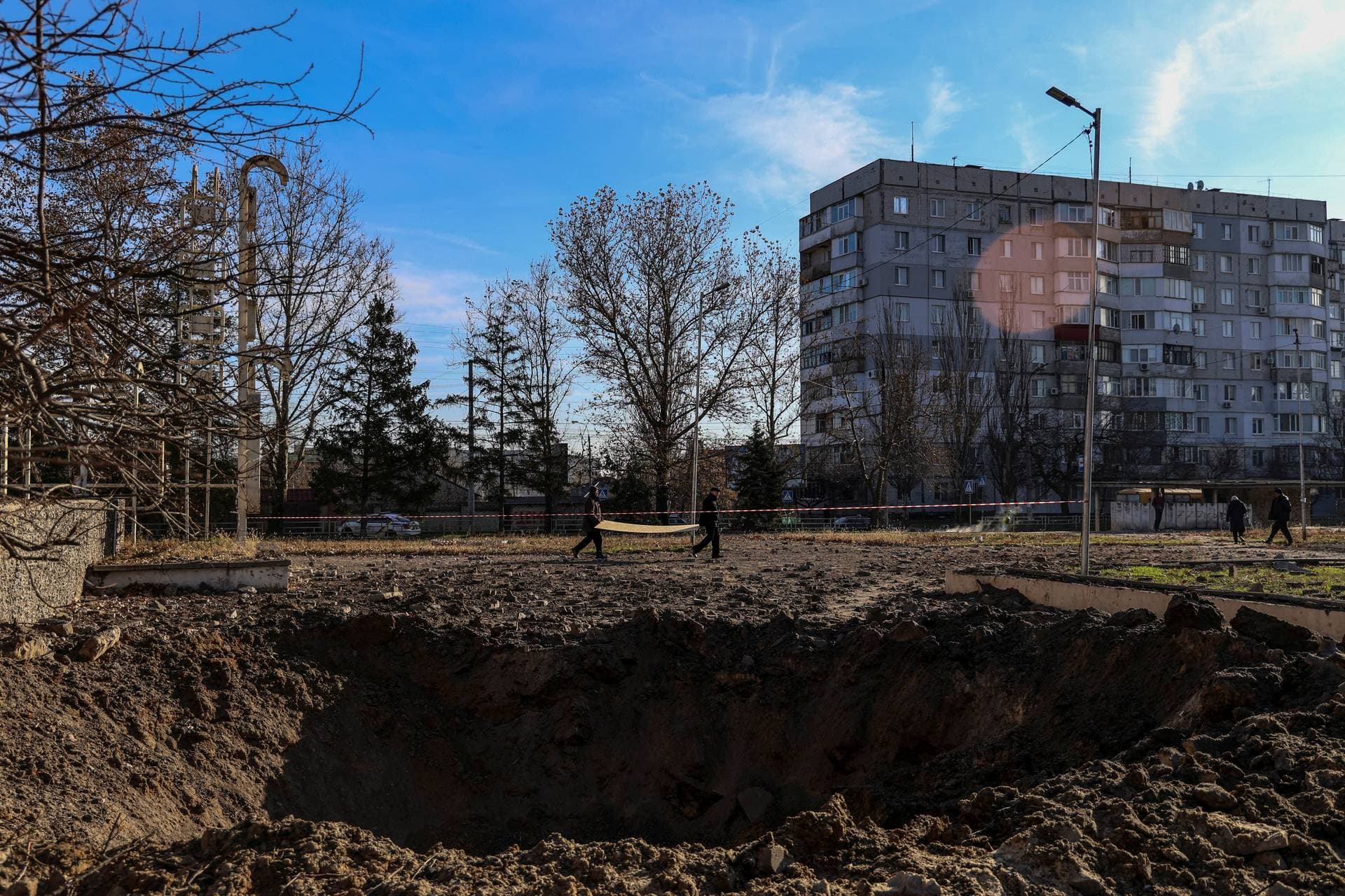 Local residents stand next a Russian missile strike crater in Kherson
