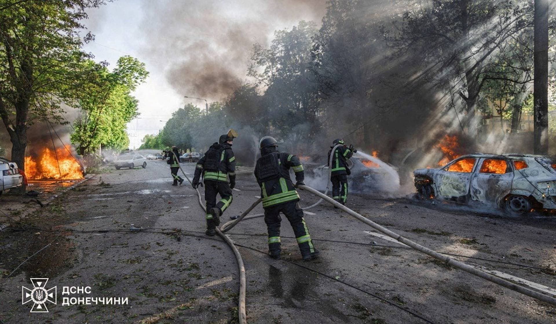 Firefighters work next to burning vehicles at a site of a Russian airstrike in the frontline city of Kramatorsk