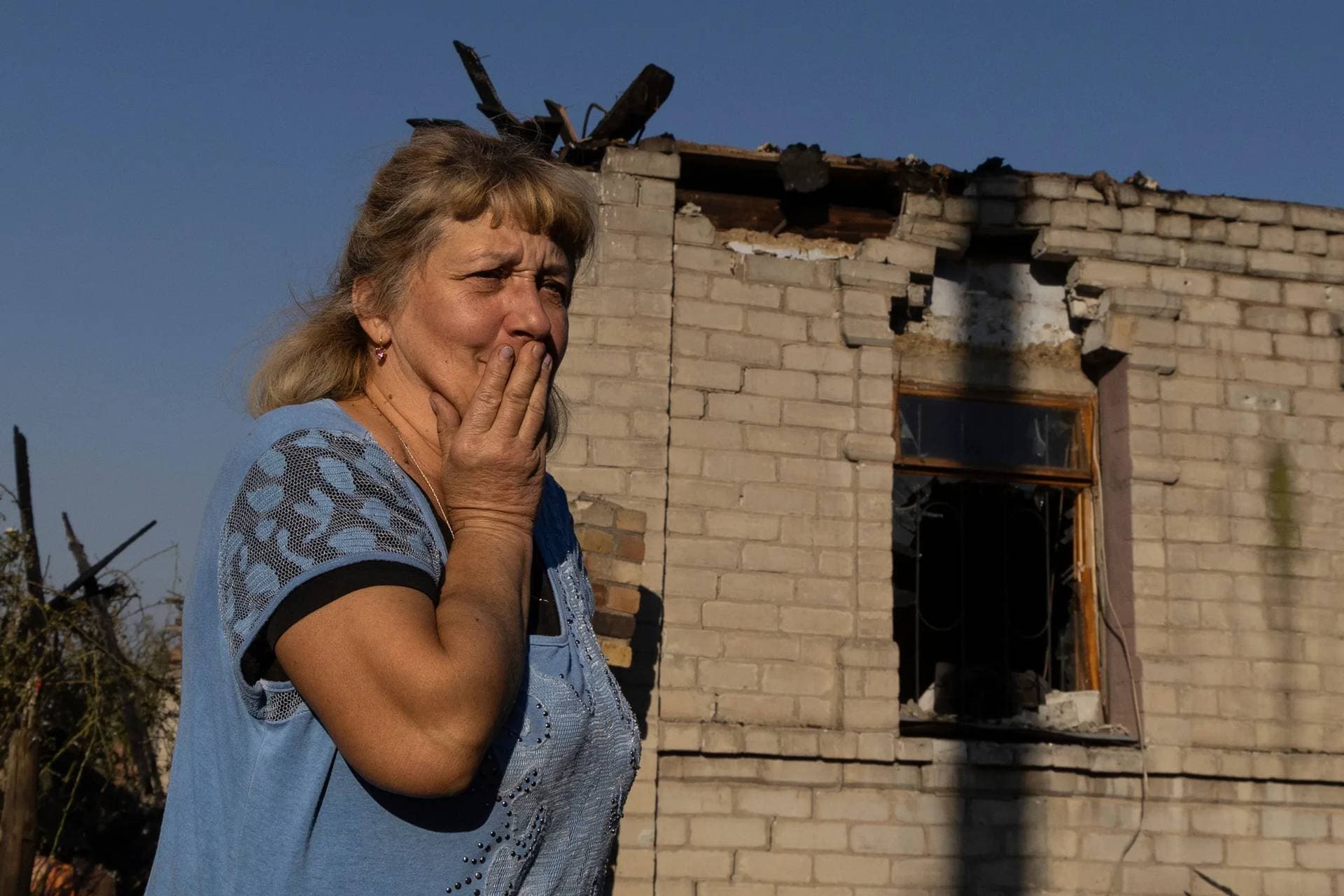 Olena Kononenko, 61, reacts in the yard of her house damaged by a Russian rocket attack in Kostiantynivka