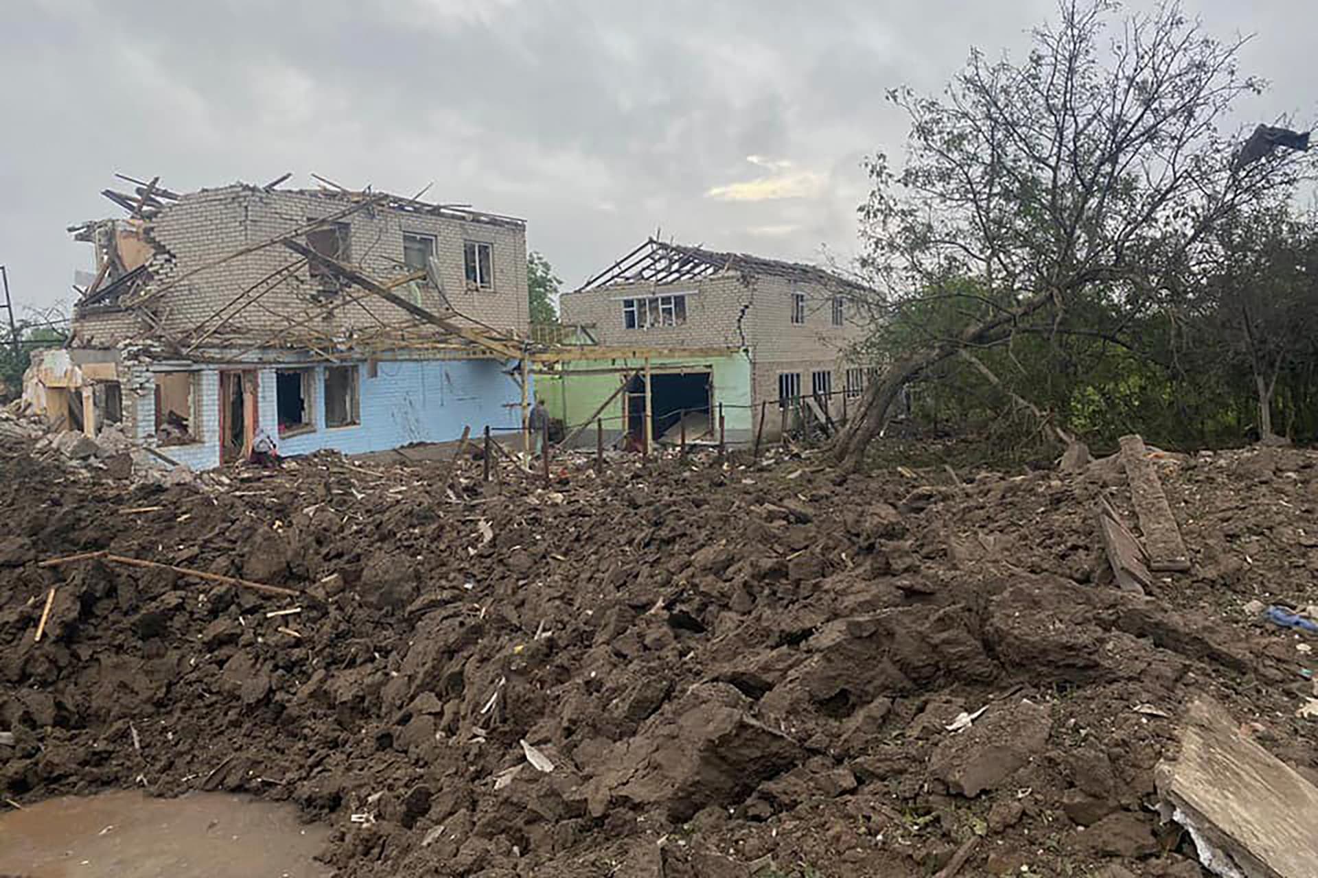 A rocket crater is seen against the background of the private houses damaged in the deadly morning Russian rocket attack in Kramatorsk