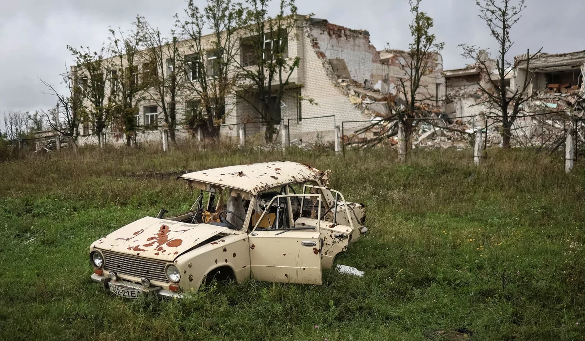 A car in front of a destroyed school in the village of Dolyna