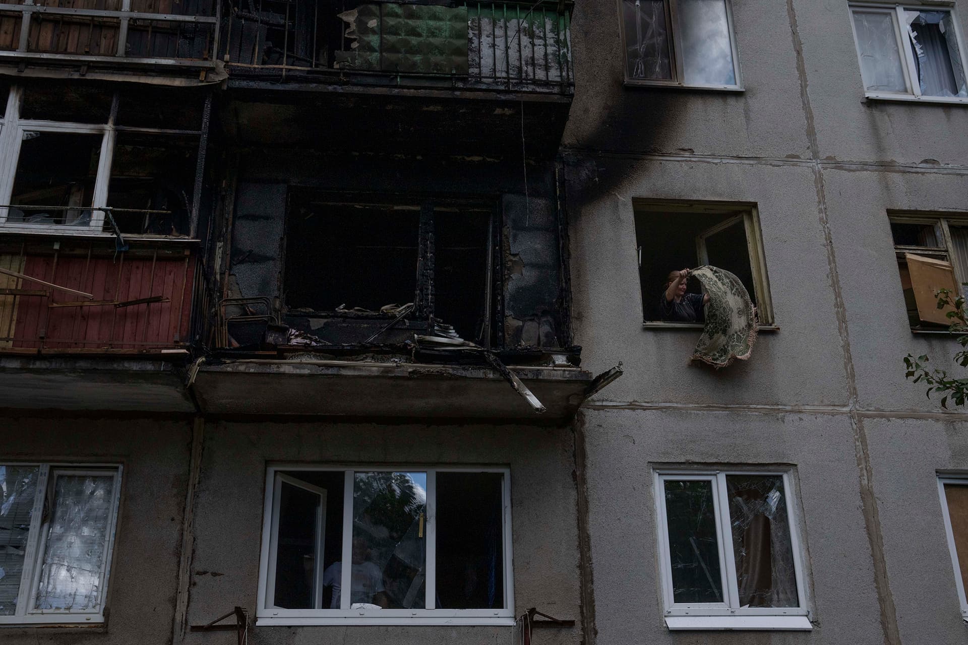 A woman salvages what she can from her damaged apartment, after a rocket hit her five-story residential building, in Kramatorsk