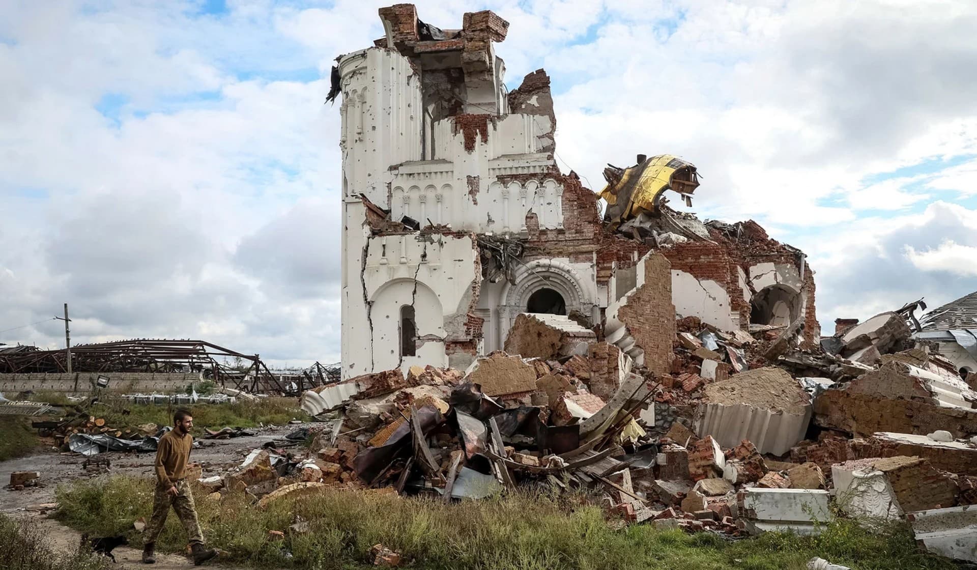 A Ukrainian serviceman passes by a destroyed church in the village of Dolyna