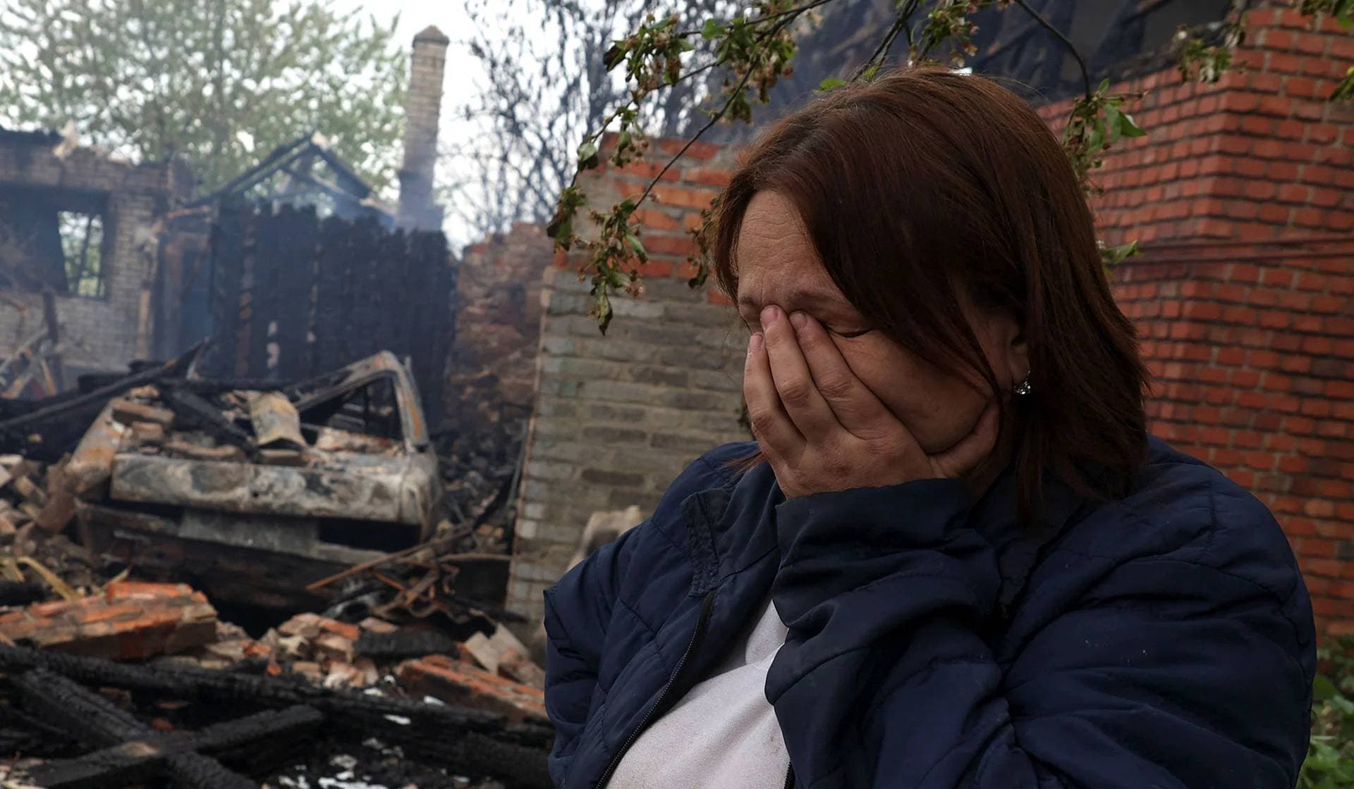 Natalia Kulinchenko reacts next to a house of her relative destroyed by a Russian drone strike in the village of Malotaranivka