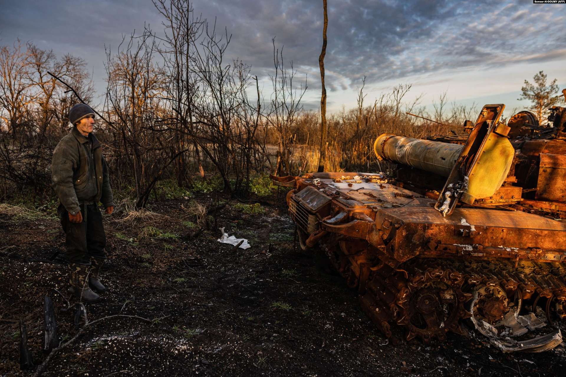 a resident of Bohorodychne looks at a destroyed Russian tank