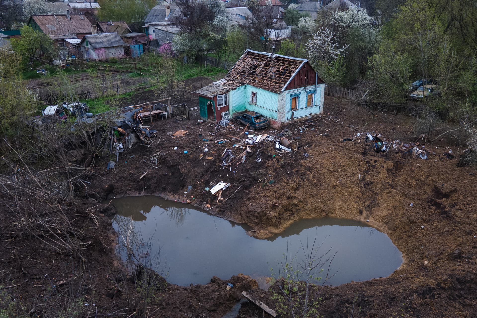 A partially destroyed house and crater after missile raids in the town of Kostyantynivka