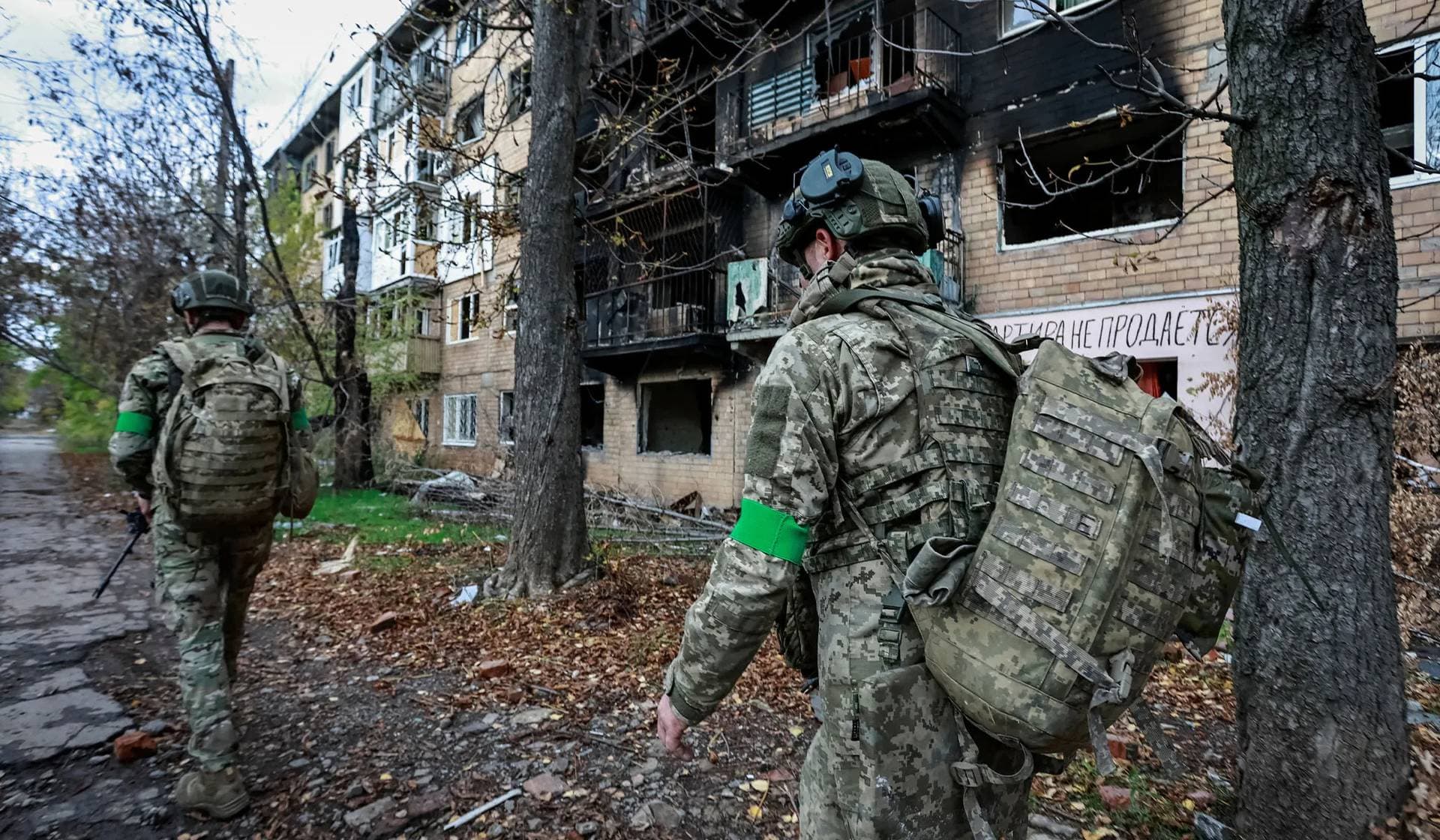 Ukrainian servicemen walk near an apartment building damaged by a Russian military strike in the frontline town of Kostiantynivka