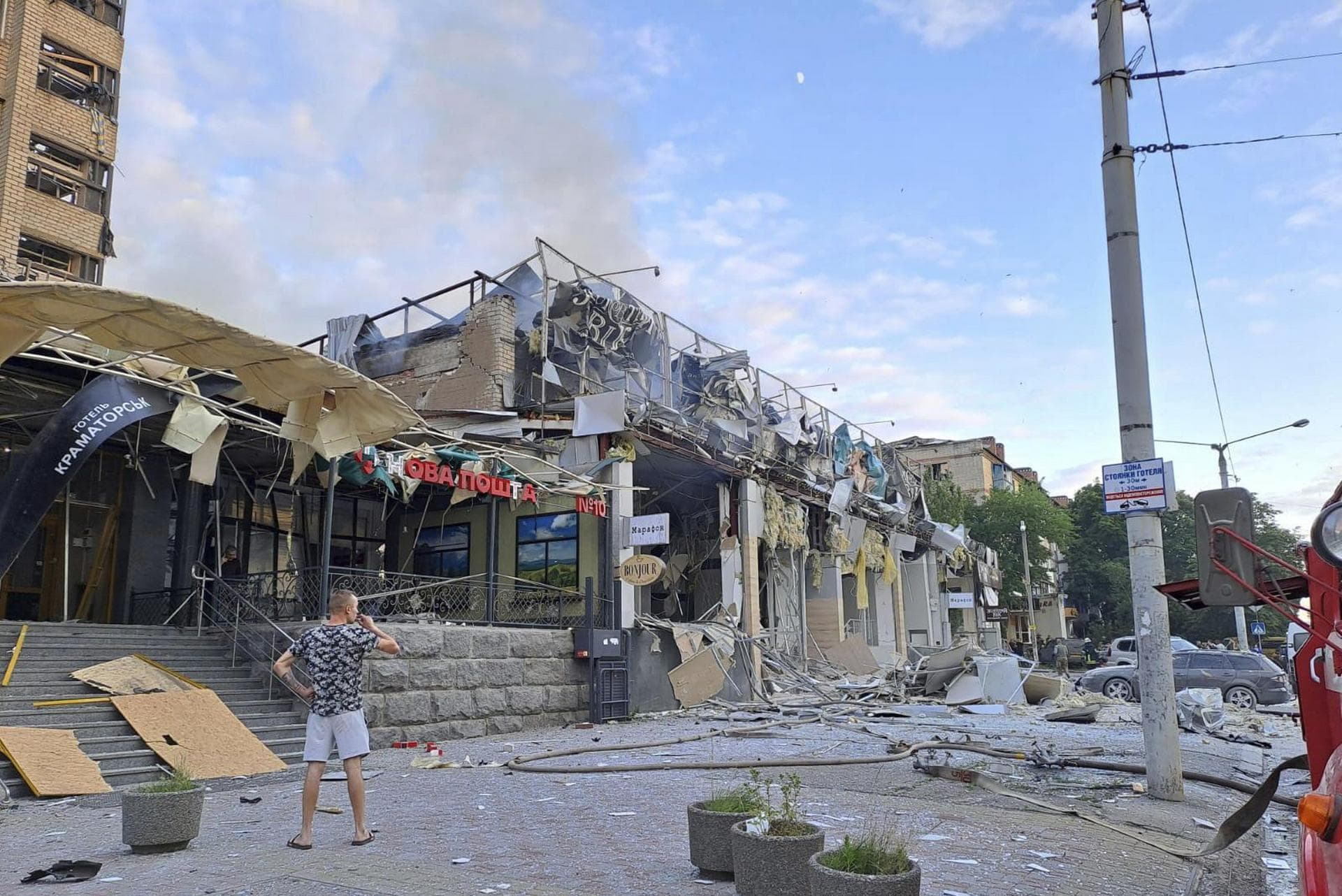 A man stands on a street in front of a shop and pizza restaurant destroyed by a Russian attack in Kramatorsk